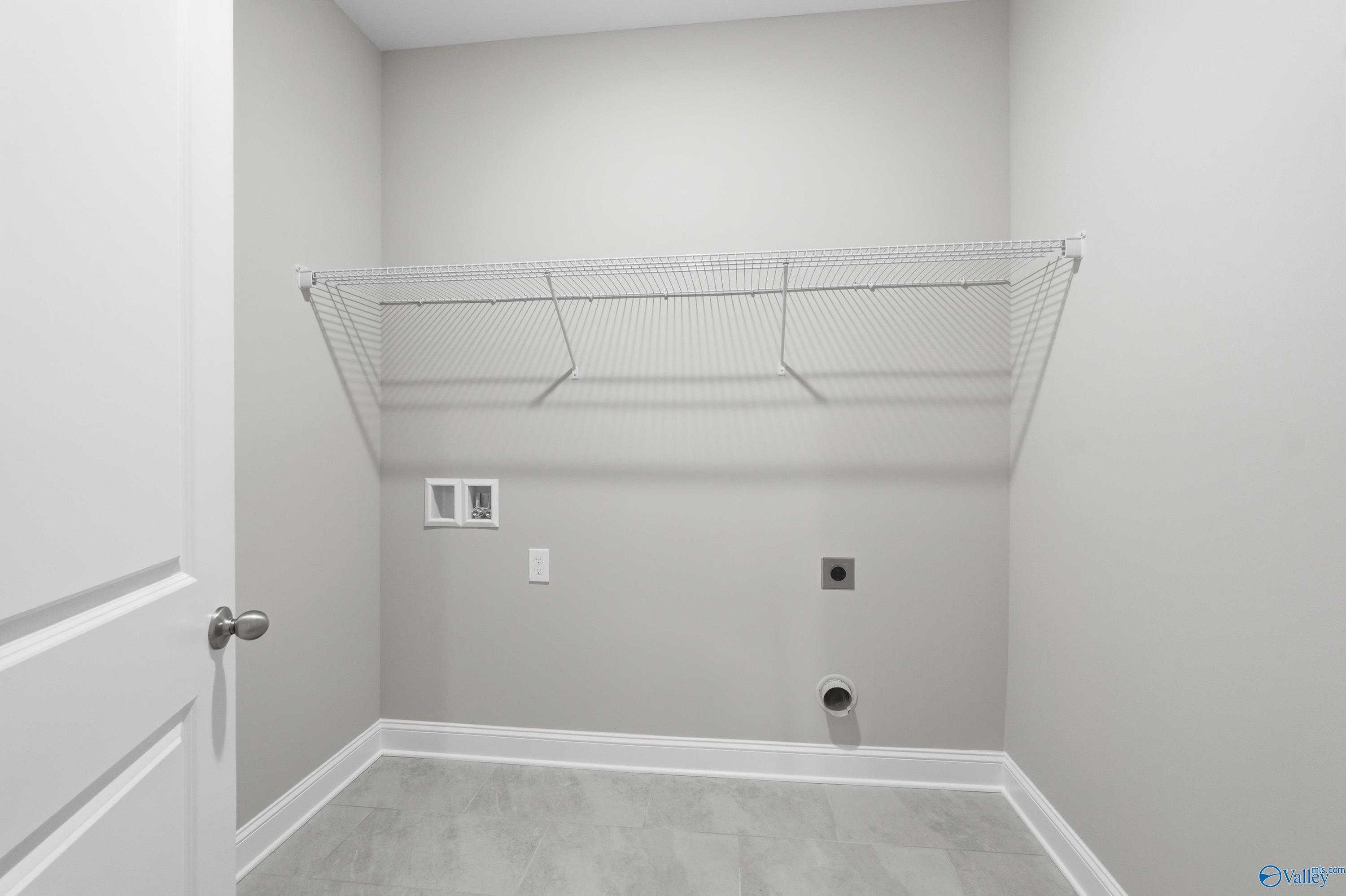 Spacious laundry room with wire shelving, washer/dryer outlets in The Lanier floor plan, Davidson Homes, Toney, Alabama