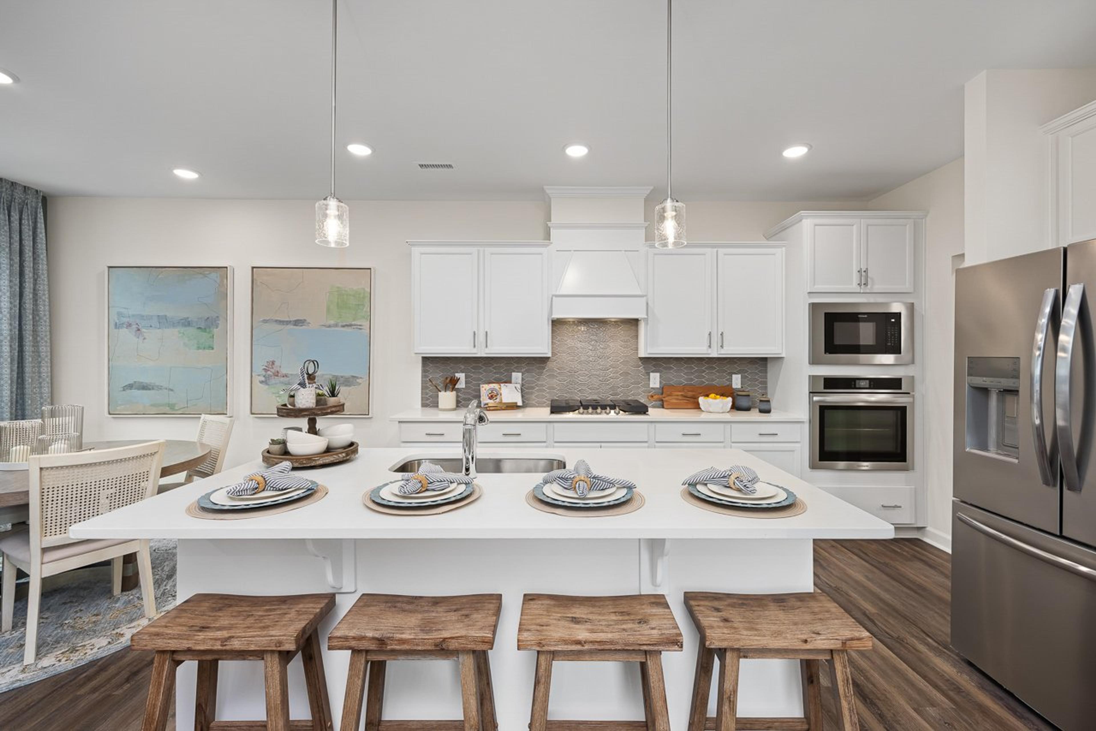 Modern kitchen at Gregory Village Townhomes in Lillington NC with white cabinets, large island, bar stools, and stainless appliances