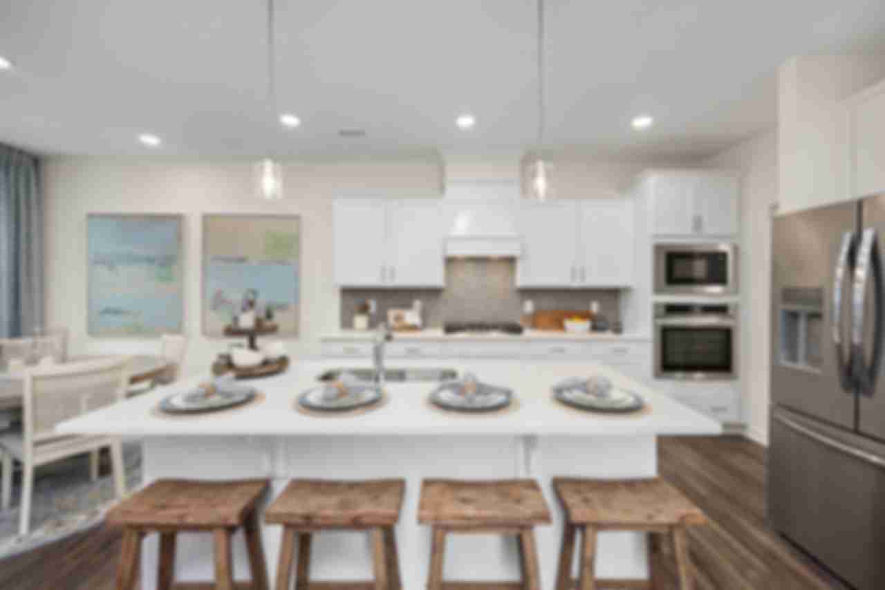 Modern kitchen at Gregory Village Townhomes in Lillington NC with white cabinets, large island, bar stools, and stainless appliances