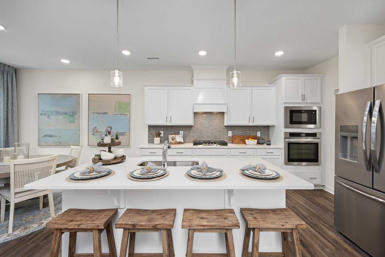 Modern kitchen at Gregory Village Townhomes in Lillington NC with white cabinets, large island, bar stools, and stainless appliances
