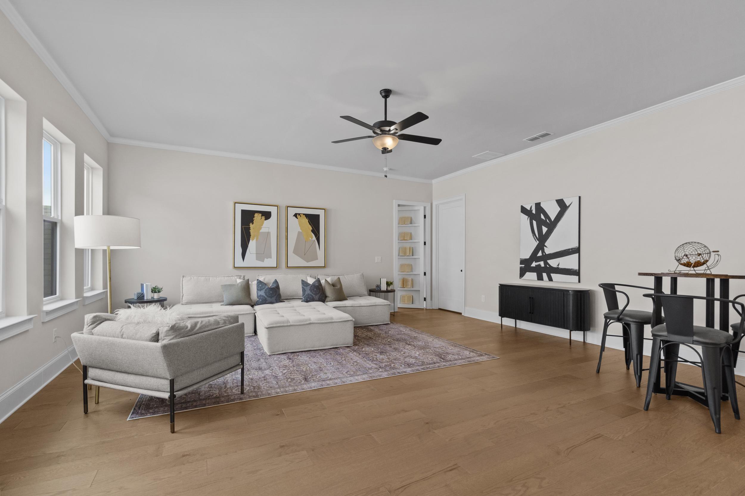Open-concept living room at The Village at Towne Lake Woodstock GA with gray sofa, abstract art, hardwood floors, ceiling fan