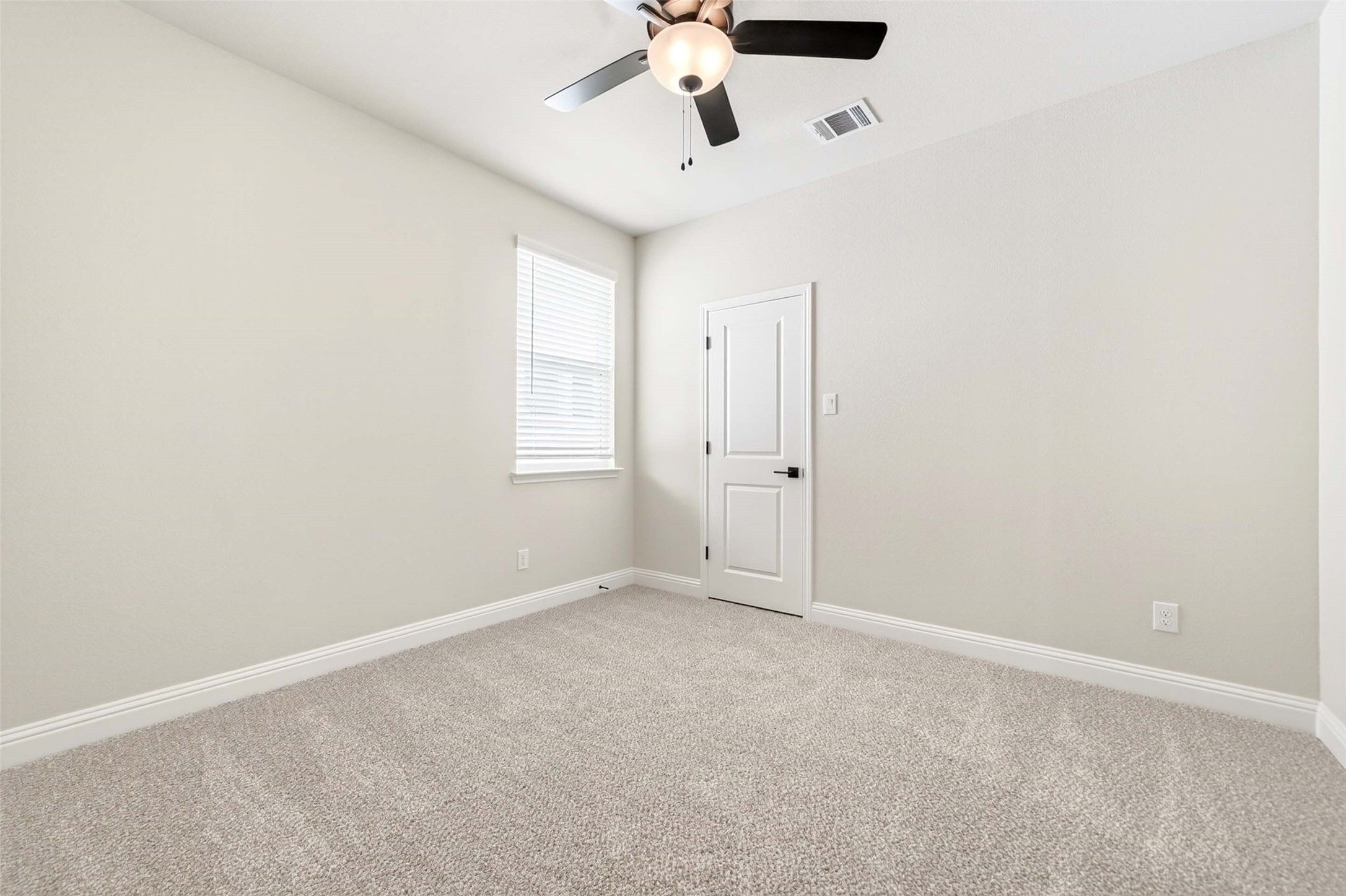 Bright, carpeted bedroom with ceiling fan in The Holly C floor plan at Parks at Foster Crossing in Anna, Texas.