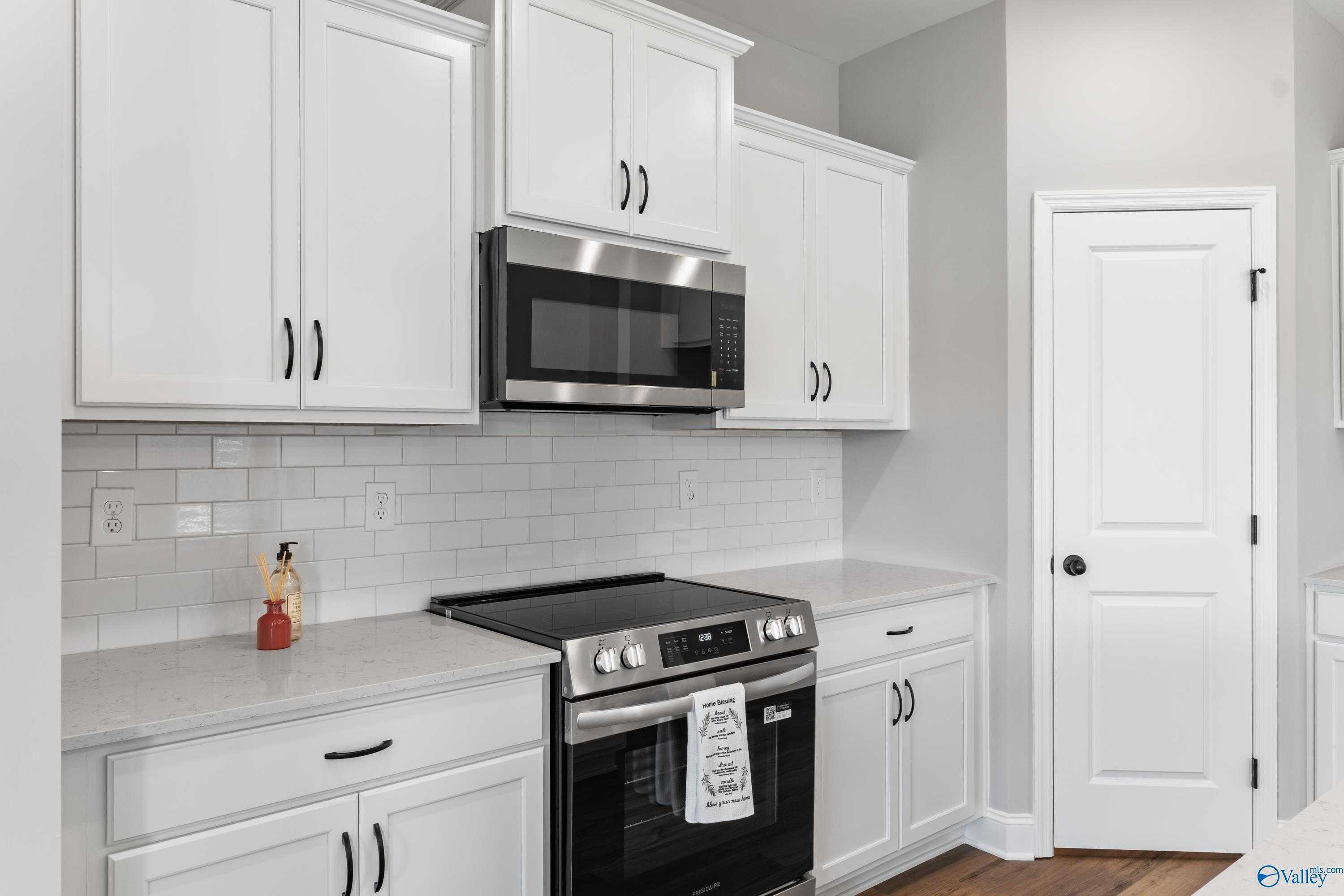 Modern white kitchen with stainless appliances, subway tile backsplash in The Franklin B by Davidson Homes, Hazel Green, AL