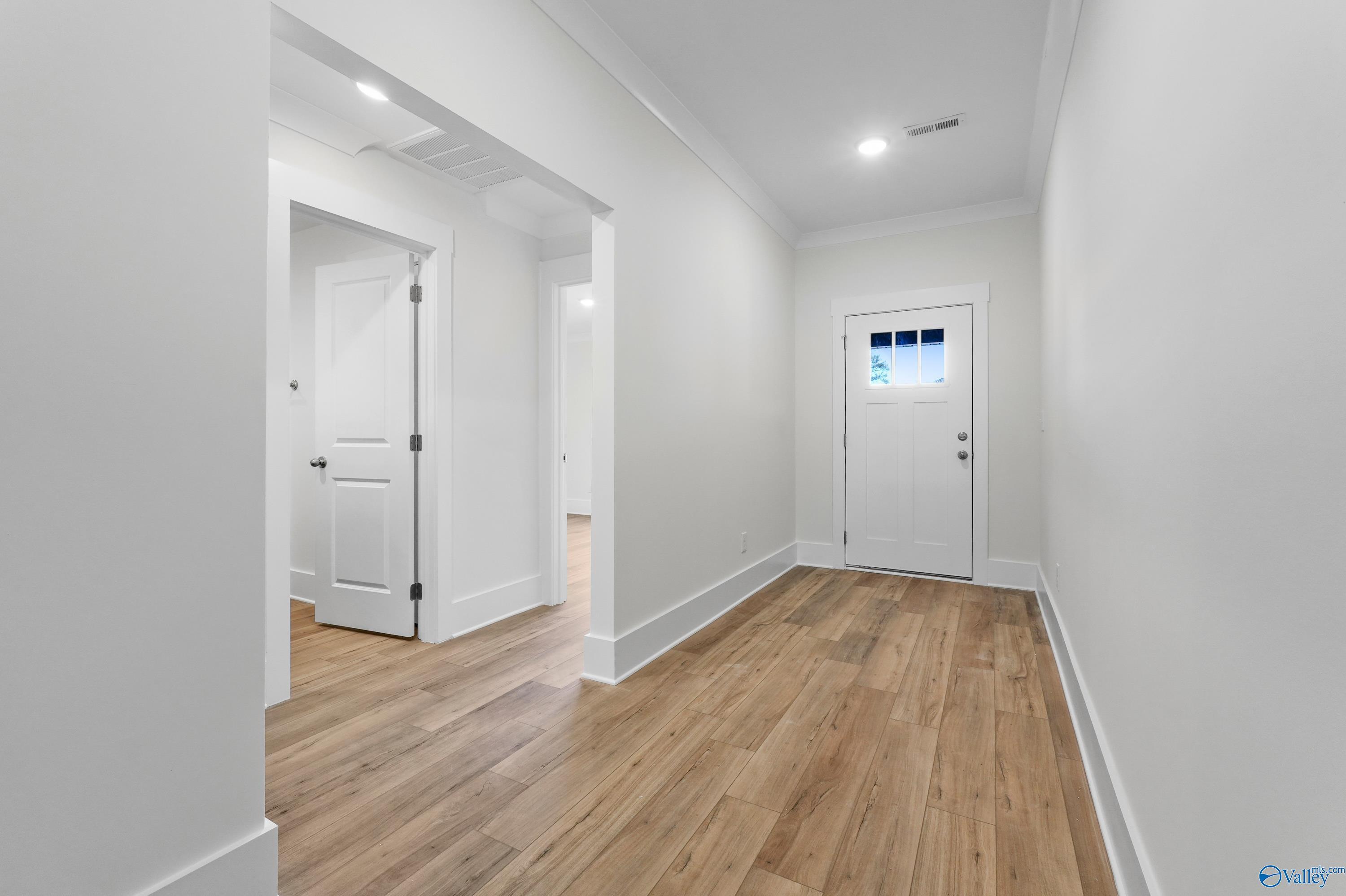 Bright hallway with hardwood floors, white walls, and open doorways in Davidson Homes The Daphne C, Arab, Alabama