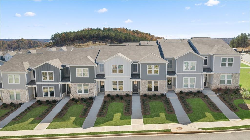 Aerial view of modern two-story townhomes with gray siding, stone accents, and green lawns in Stegall Village, Emerson, Georgia