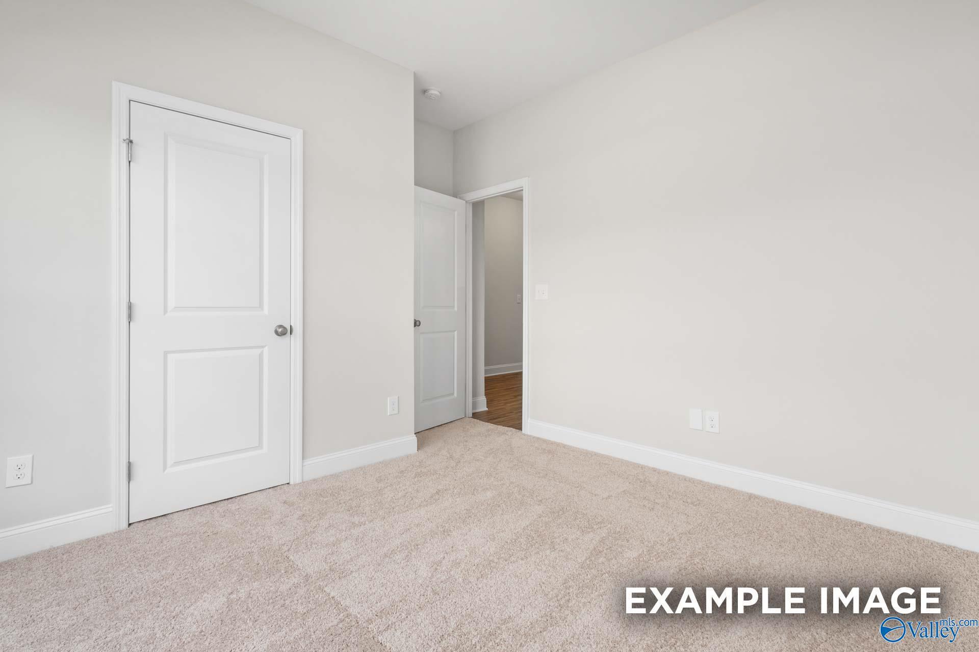 Neutral bedroom with carpeted flooring and closet doors in The Franklin floor plan at Clearview, Hazel Green, Alabama.