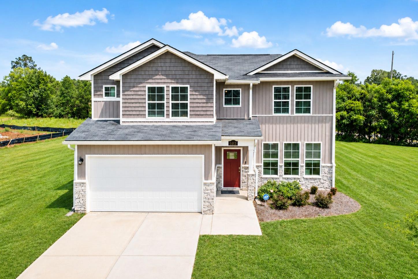 Modern two-story home exterior in Ivy Glen Perry GA by Evermore Homes with gray siding red door attached garage and manicured lawn