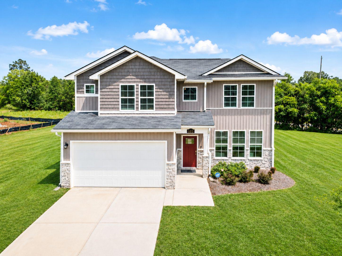 Two-story Davidson Homes exterior at Ivy Glen in Perry, Georgia, featuring gray siding, stone accents, and a red front door.