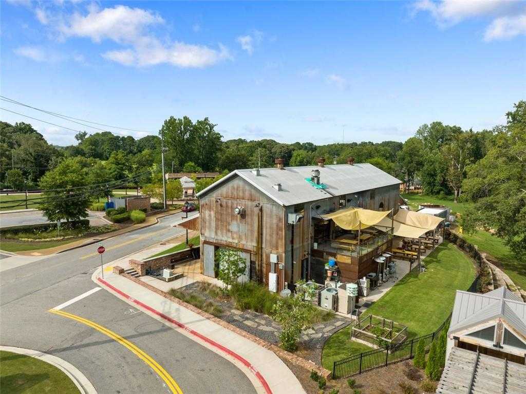 Rustic barn-style building with outdoor patio, yellow umbrellas, and lush trees in Wehunt Meadows, Hoschton, Georgia