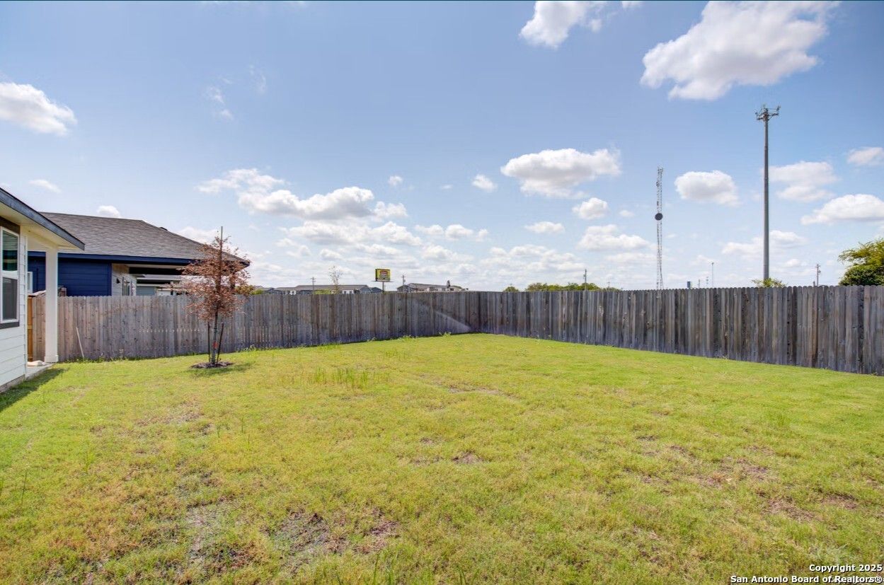 Spacious grassy backyard with wooden fence and young tree in 3-bedroom Davidson Homes The Daphne H, Hannah Heights, Seguin, Texas