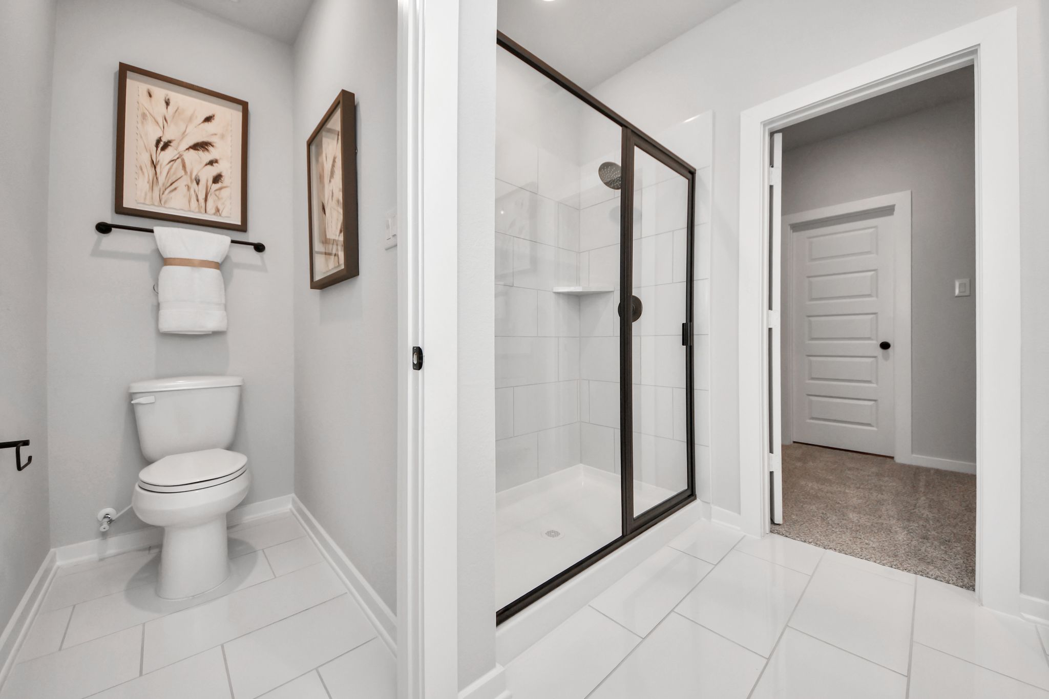 Modern bathroom at Robins Landing in Houston with walk-in glass shower, white tile flooring, and sleek finishes by Davidson.