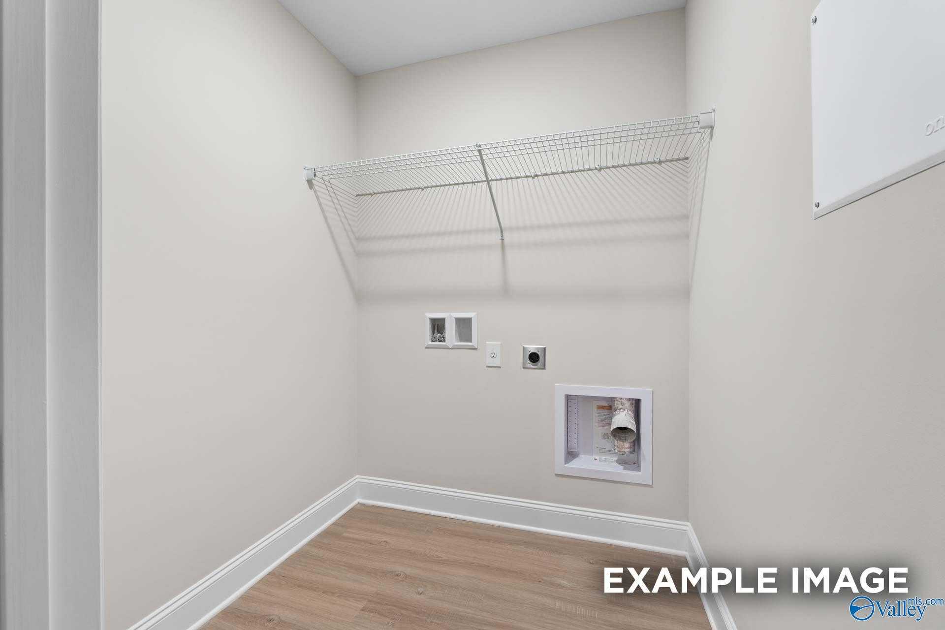 Bright laundry closet with wire shelving, washer/dryer hookups, and hardwood floors in Davidson Homes The Camden C, Huntsville AL