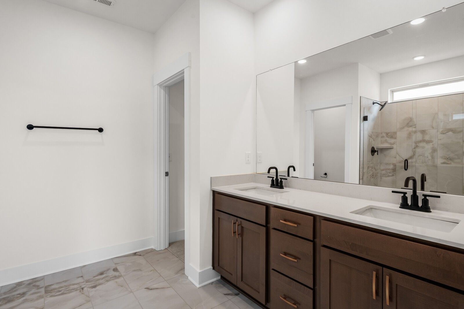 Modern primary bathroom with double vanity, dark wood cabinets, and tiled walk-in shower in Woods Crossing, Gallatin, TN.