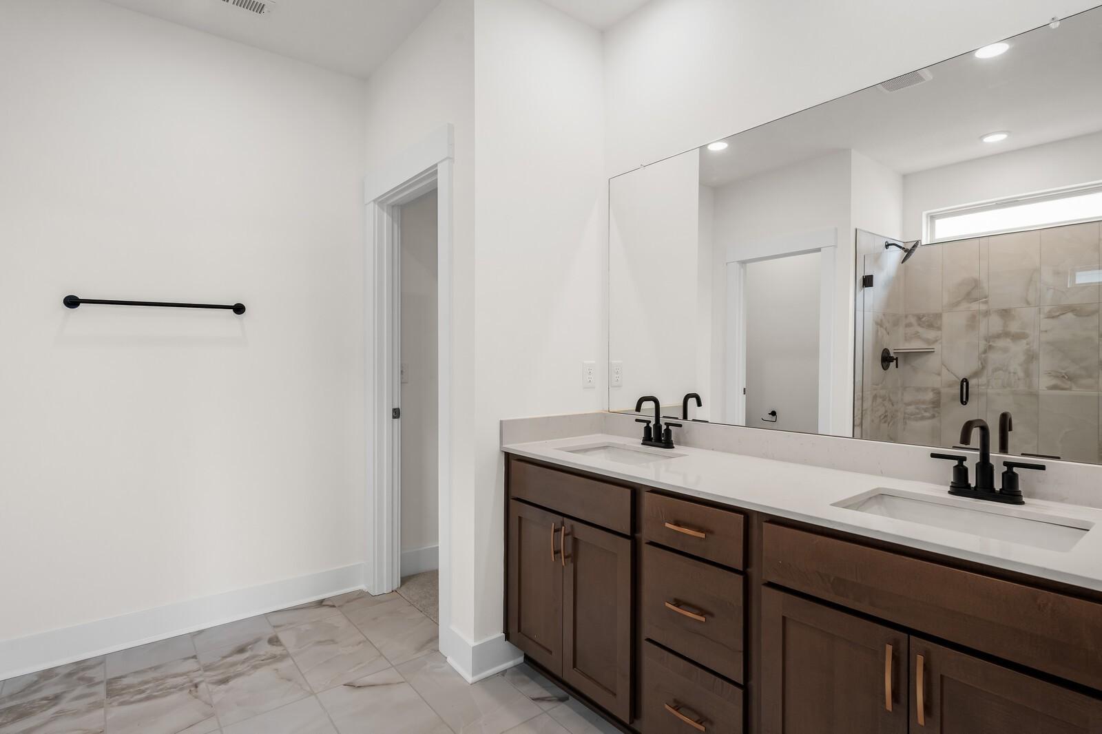 Modern primary bathroom with double vanity, dark wood cabinets, and tiled walk-in shower in Woods Crossing, Gallatin, TN.