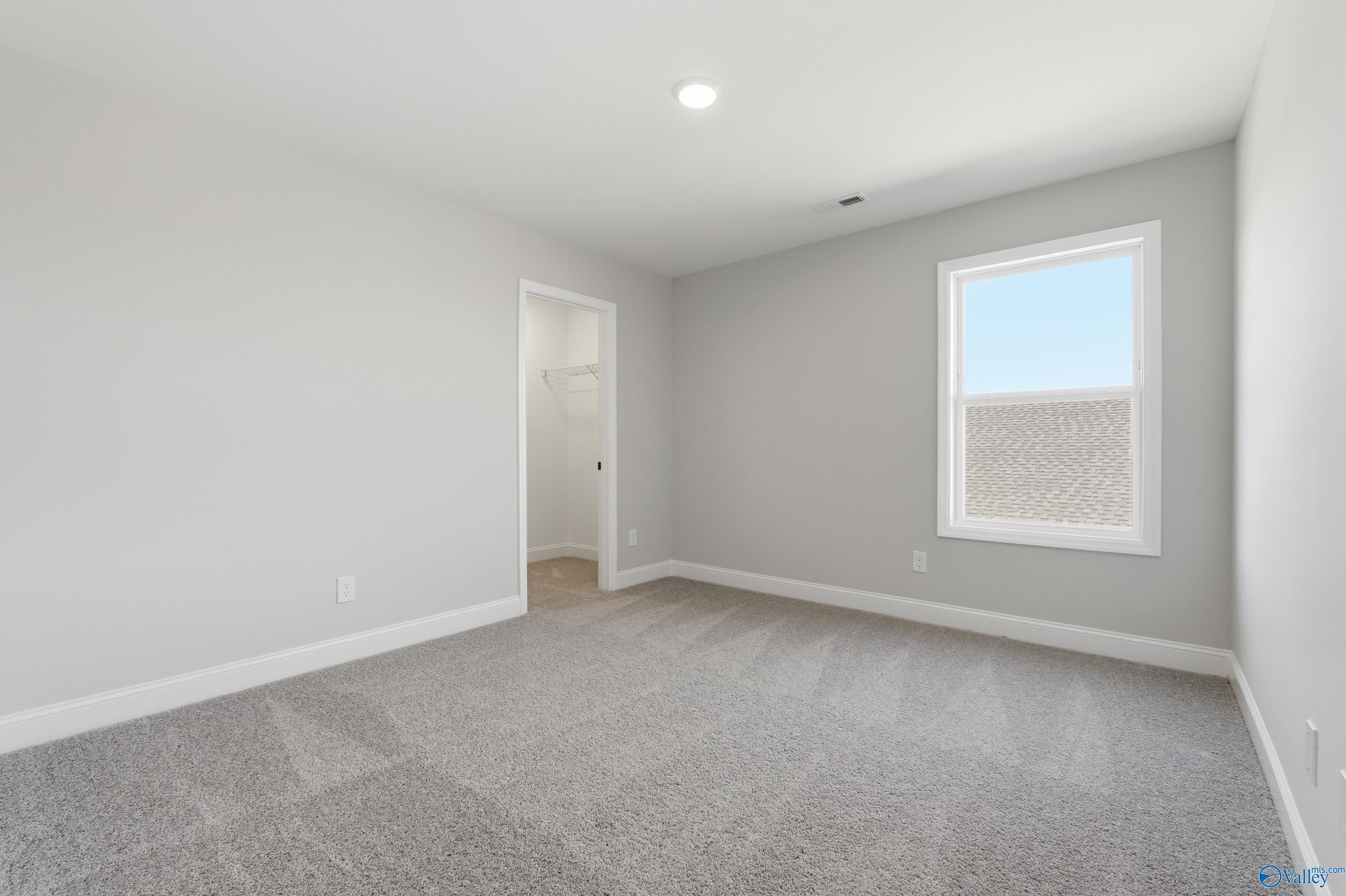 Bright secondary bedroom featuring gray walls, plush carpet, large window with blue sky view in Davidson Homes The Chelsea C, Harvest AL