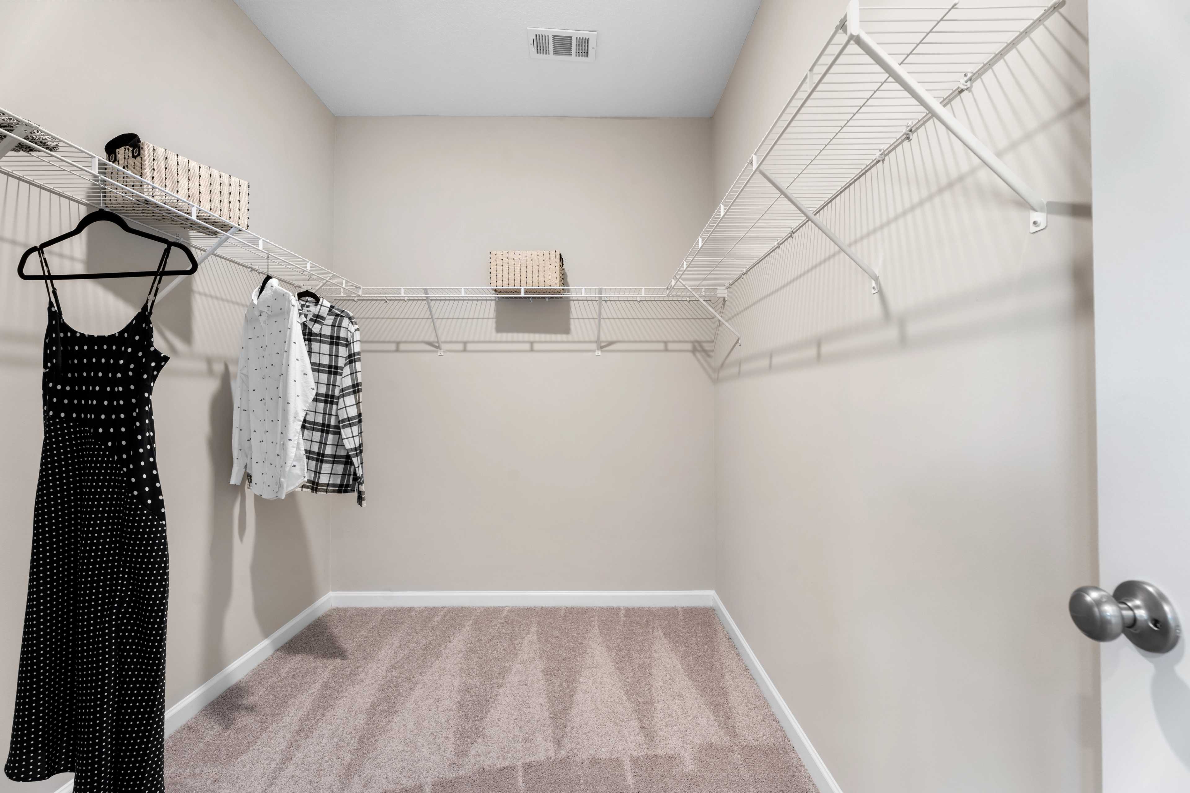 Spacious walk-in closet in Silver Oak Cusseta AL home with wire shelving, hanging clothes and storage baskets by Evermore Homes