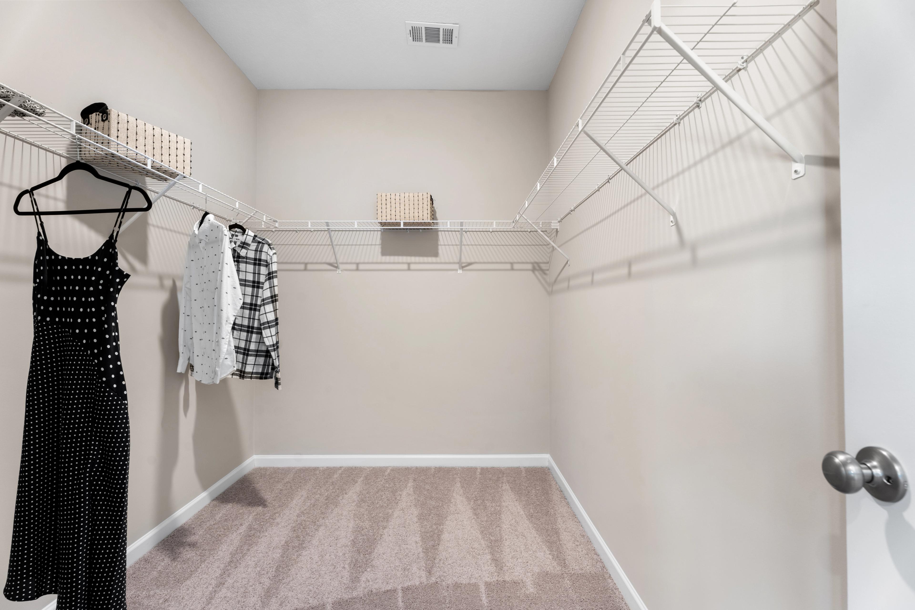 Spacious walk-in closet in Silver Oak Cusseta AL home with wire shelving, hanging clothes and storage baskets by Evermore Homes