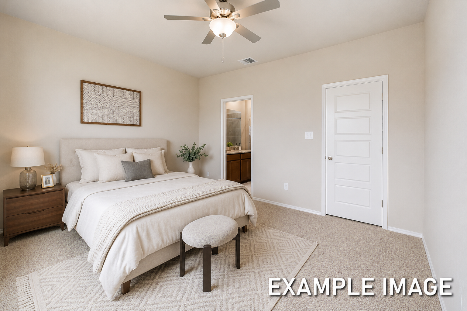 Spacious master suite on the main floor of The Comal featuring neutral decor, plush bedding, and an attached bathroom.