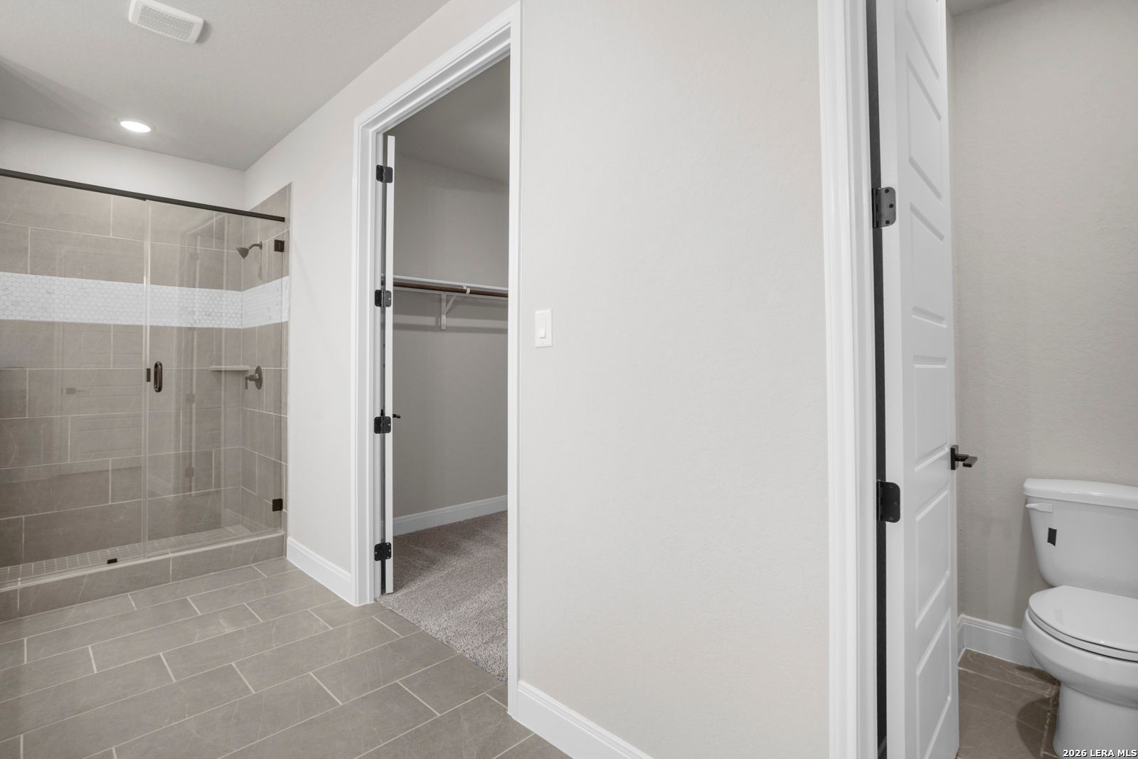 Primary bathroom with glass-enclosed shower, tile flooring, and walk-in closet in The Jennings G floor plan, Ladera.