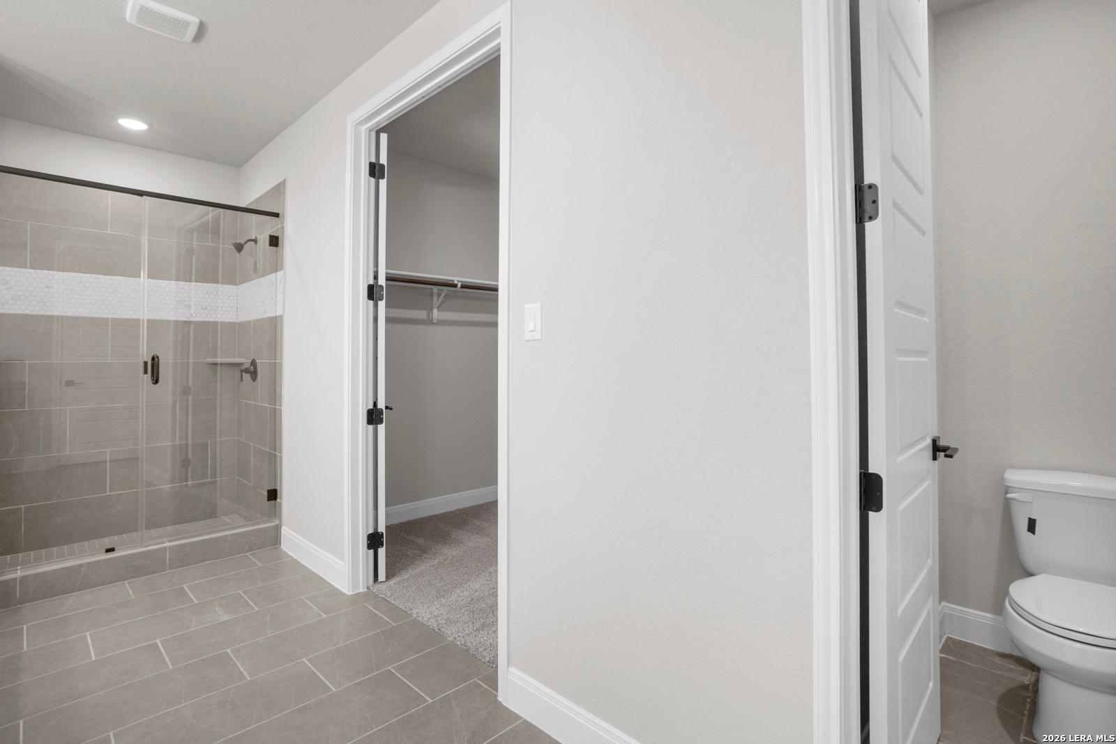 Primary bathroom with glass-enclosed shower, tile flooring, and walk-in closet in The Jennings G floor plan, Ladera.