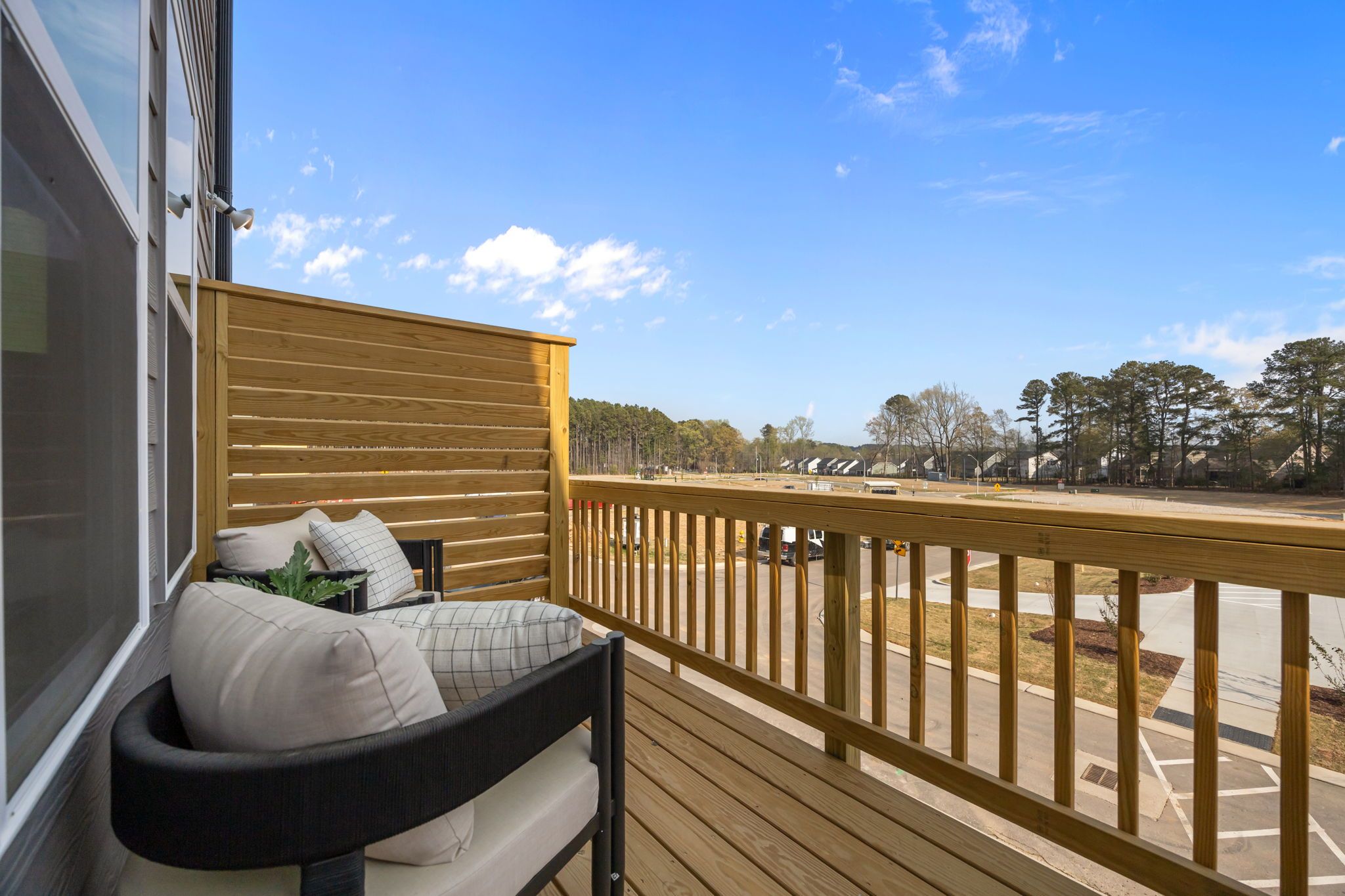 Spacious wooden deck balcony at Camden Park in Knightdale NC with cushioned lounge chairs and pine forest view