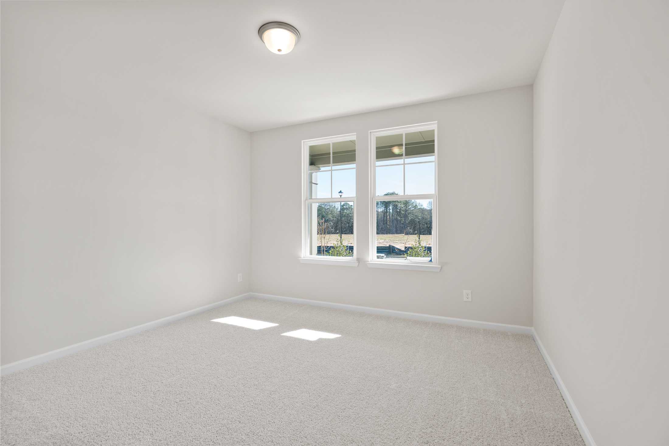Bright spacious bedroom in The Dawson C with large windows, natural light, beige carpet, and white walls