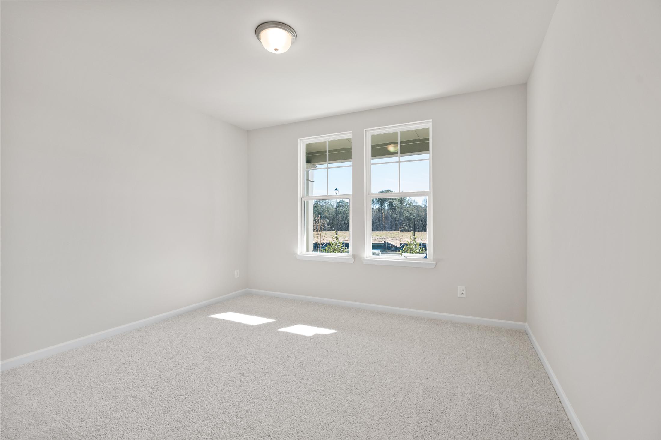 Bright spacious bedroom in The Dawson C with large windows, natural light, beige carpet, and white walls