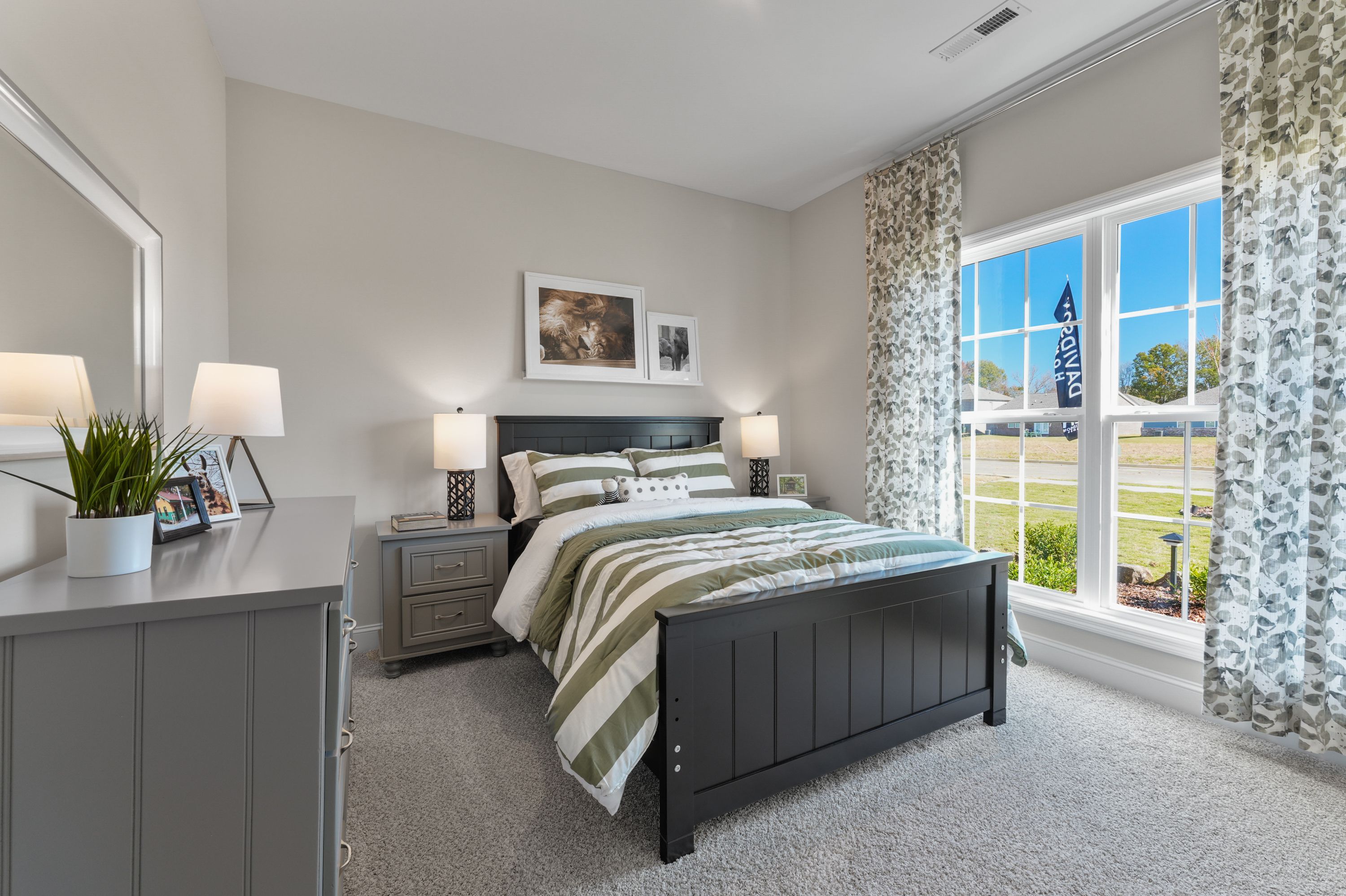 Spacious bedroom in Ramsay Cove, Owens Cross Roads AL featuring black bed frame, striped bedding, and large window view