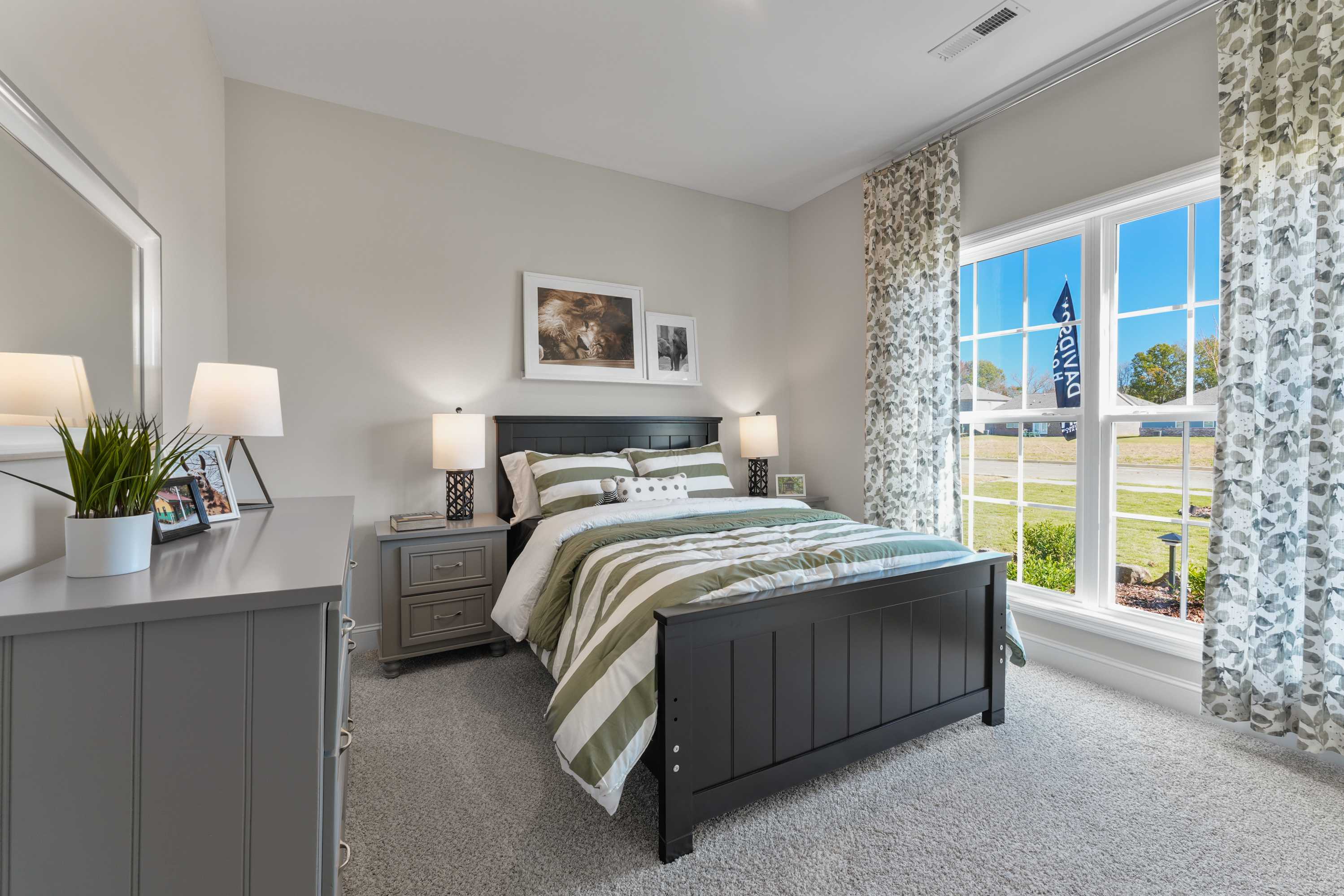 Spacious bedroom in Ramsay Cove, Owens Cross Roads AL featuring black bed frame, striped bedding, and large window view