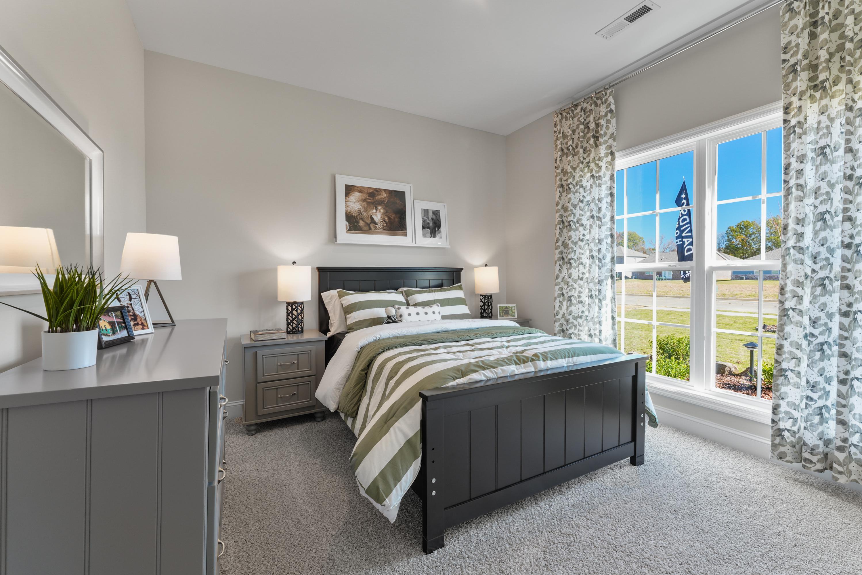 Spacious bedroom in Ramsay Cove, Owens Cross Roads AL featuring black bed frame, striped bedding, and large window view