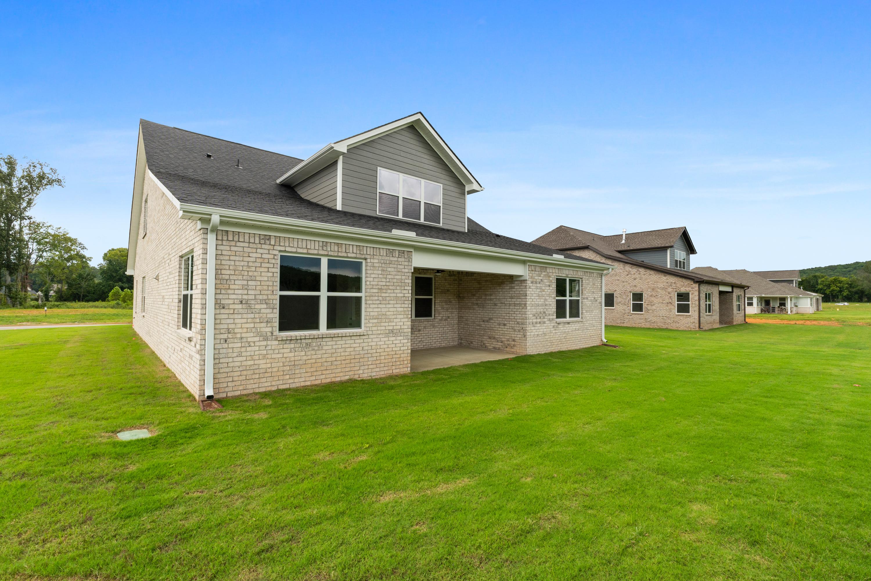 Two-story Oxford B home elevation by Evermore Homes, brick and gray siding exterior, covered porch, green lawn in Owens Cross Roads, Alabama