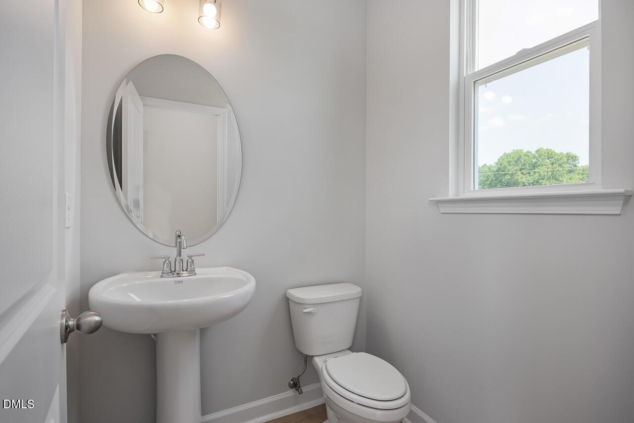 Modern half-bath with pedestal sink and oval mirror in The Mitchell floor plan at Camden Park, Knightdale, North Carolina.