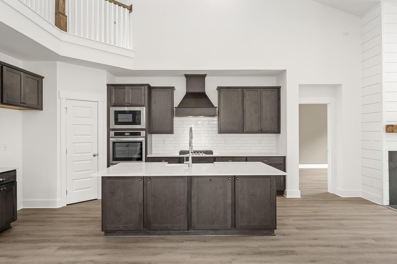 Modern kitchen with dark cabinets, quartz island, and white subway tile in The Ridgeport C home by Davidson Homes, Gallatin.