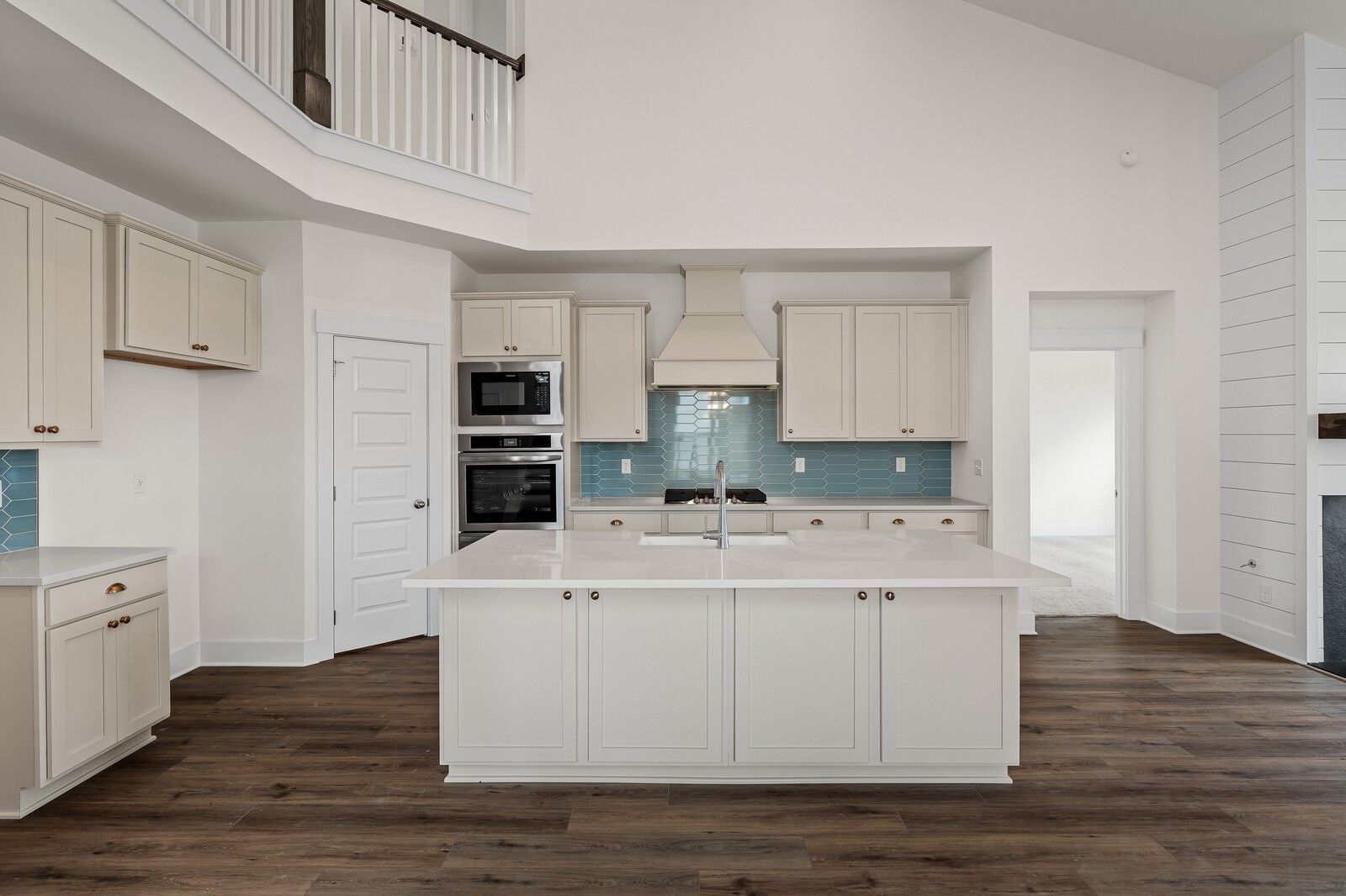 Modern white kitchen with large island sink, blue backsplash, double oven in Davidson Homes The Ridgeport, Gallatin, TN