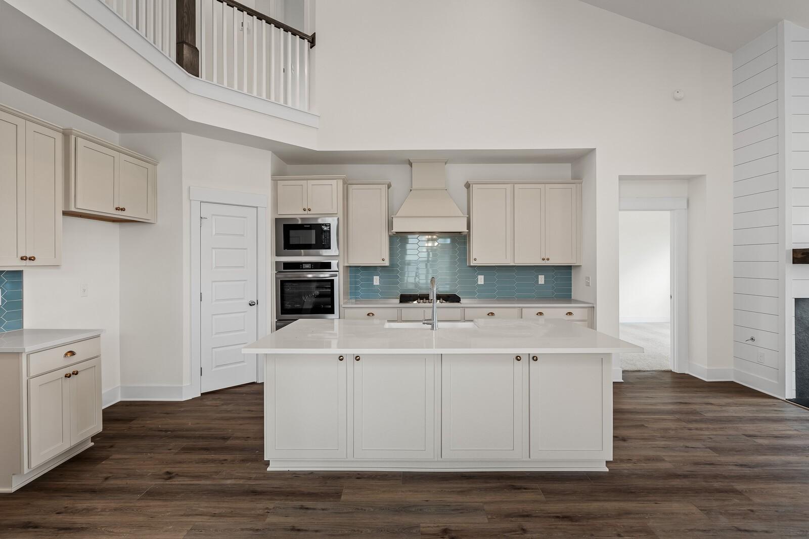 Modern white kitchen with large island sink, blue backsplash, double oven in Davidson Homes The Ridgeport, Gallatin, TN