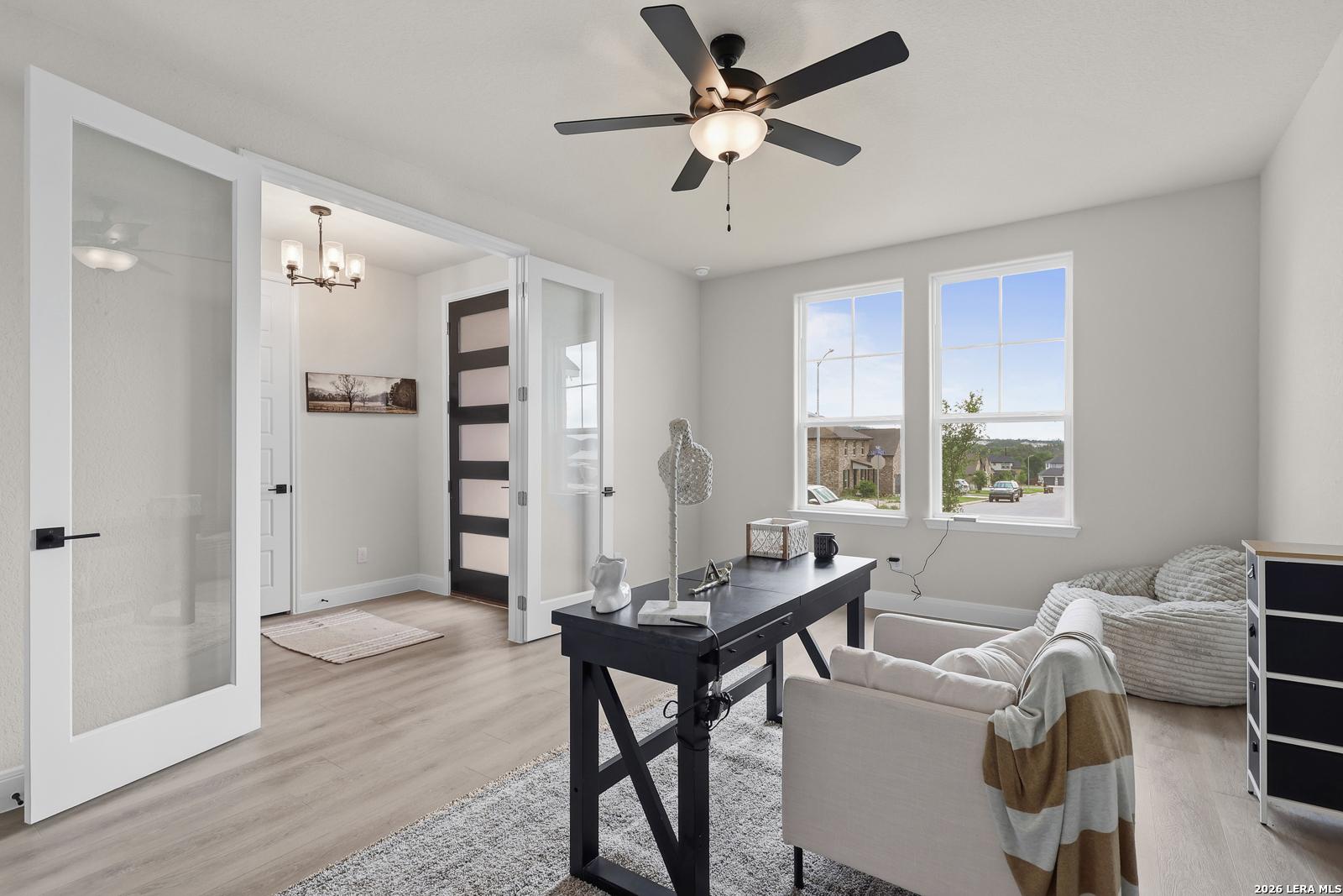 Cozy home office with black desk, white armchair, bean bag, and large windows in Davidson Homes The Lanier G, Castroville, Texas