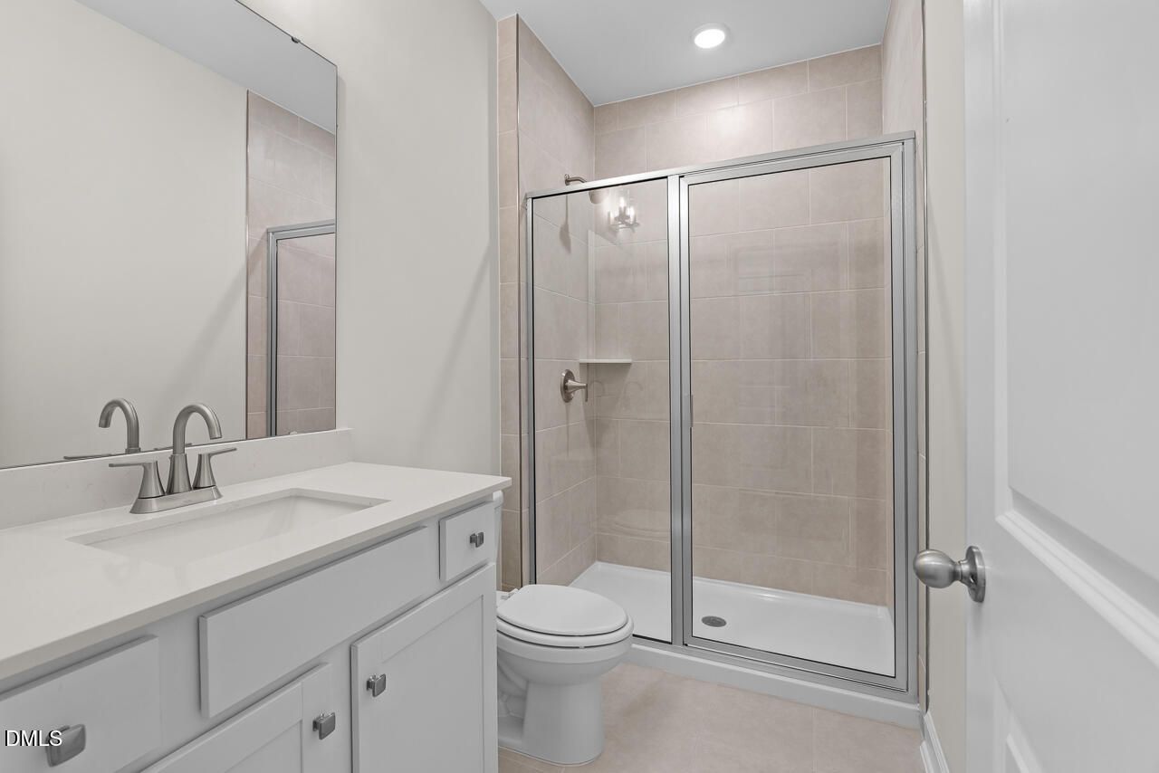 Modern bathroom with glass walk-in shower, white vanity, and tiled walls in Davidson Homes Preston B plan, Wendell Ridge, NC