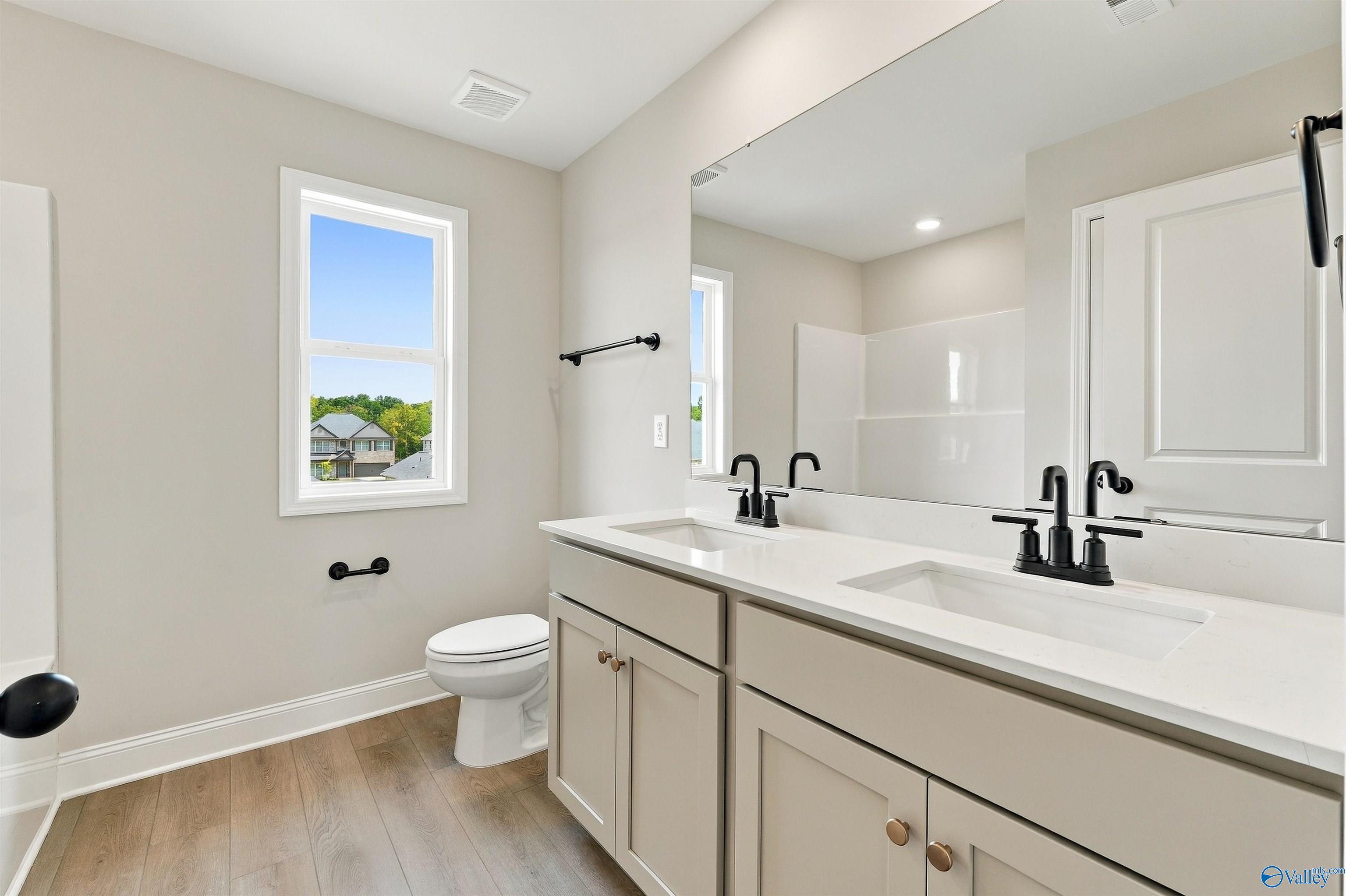 Double vanity bathroom with matte black faucets, taupe cabinets, and luxury vinyl flooring in Davidson Homes The Shelby A, Athens