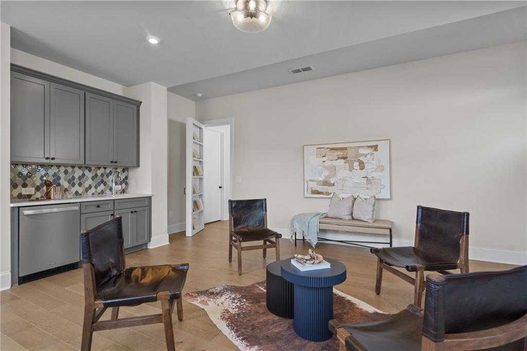 Elegant butler's pantry featuring gray cabinets, blue mosaic backsplash, leather chairs, and round table in Davidson Homes The Seaside B, Woodstock, GA