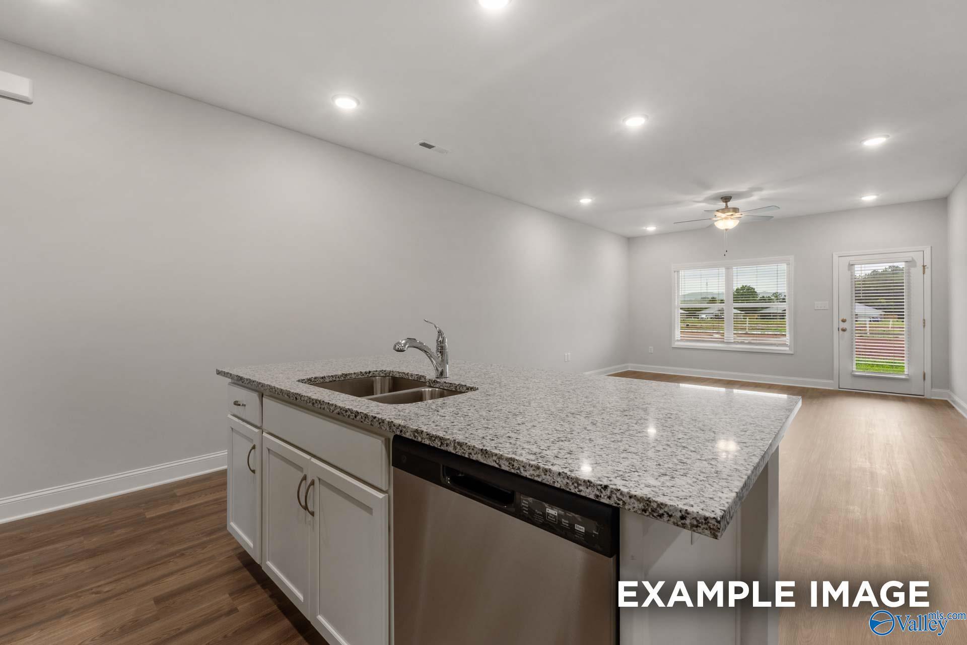 Open-concept kitchen with granite island, white cabinets, stainless dishwasher in Davidson Homes Cumberland B, Decatur, AL