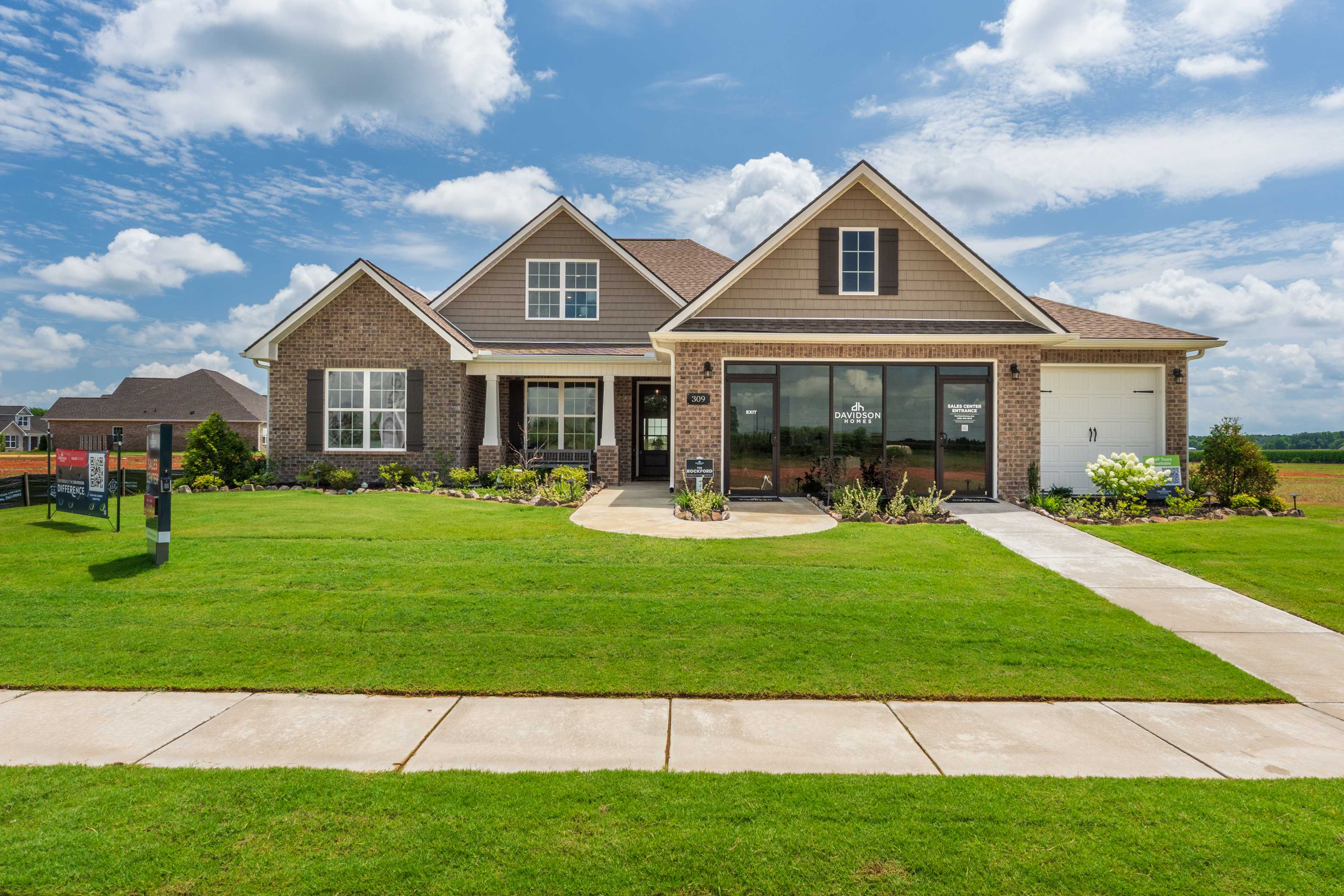 Craftsman brick home exterior at Kendall Farms in Toney Alabama with gabled roof large windows and manicured lawn