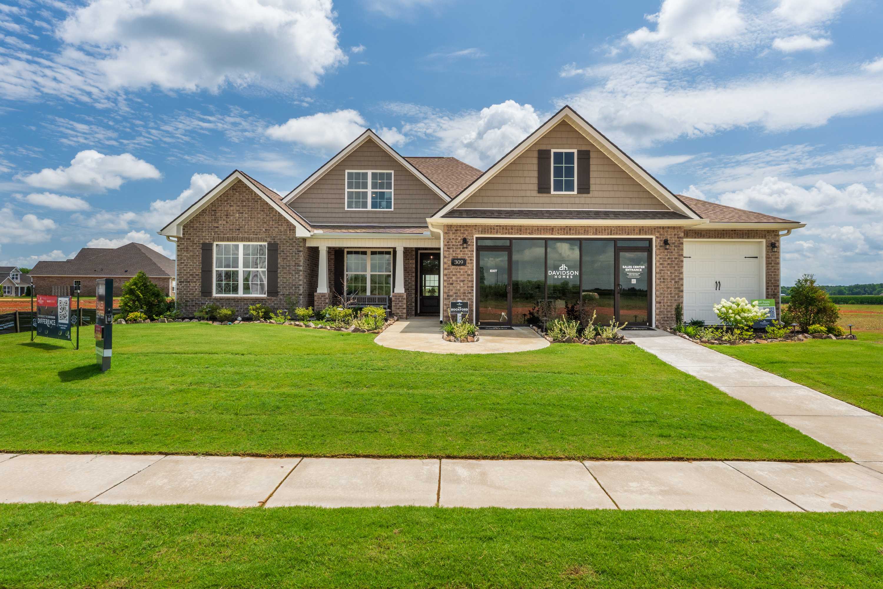 Craftsman brick home exterior at Kendall Farms in Toney Alabama with gabled roof large windows and manicured lawn