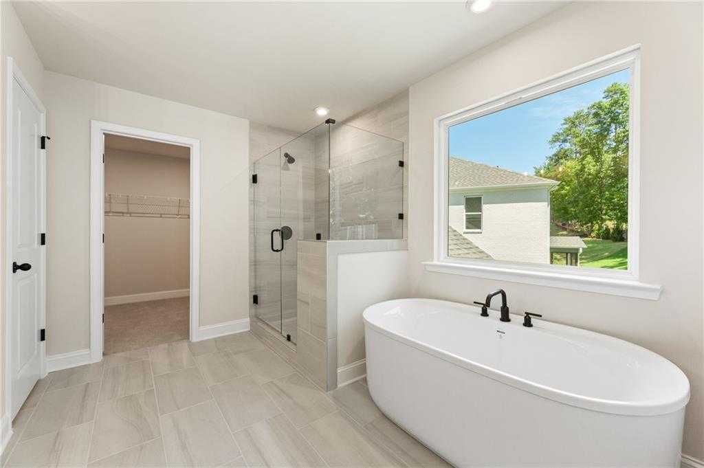 Luxurious master bathroom with freestanding soaking tub, frameless glass shower, and backyard view in Davidson Homes The Hickory E, Buford, GA