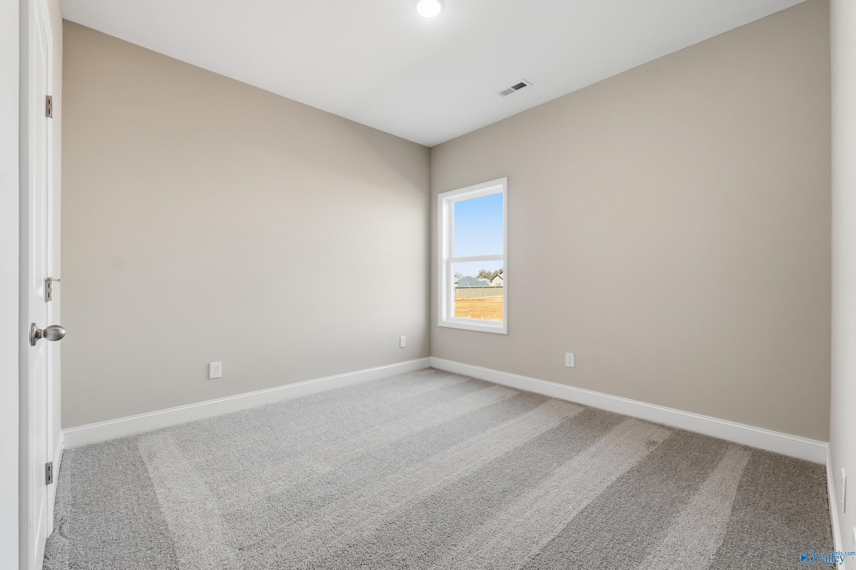 Bright secondary bedroom with beige walls, gray carpet, and large window overlooking field in Davidson Homes Franklin C, New Market, Alabama