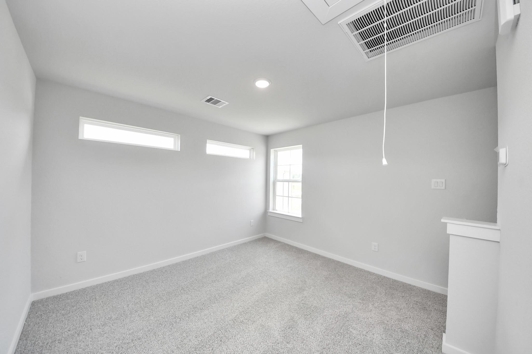 Bright, carpeted bedroom with natural light in The Sabine F floor plan by Davidson Homes, Liberty Estates, Cleveland, TX.