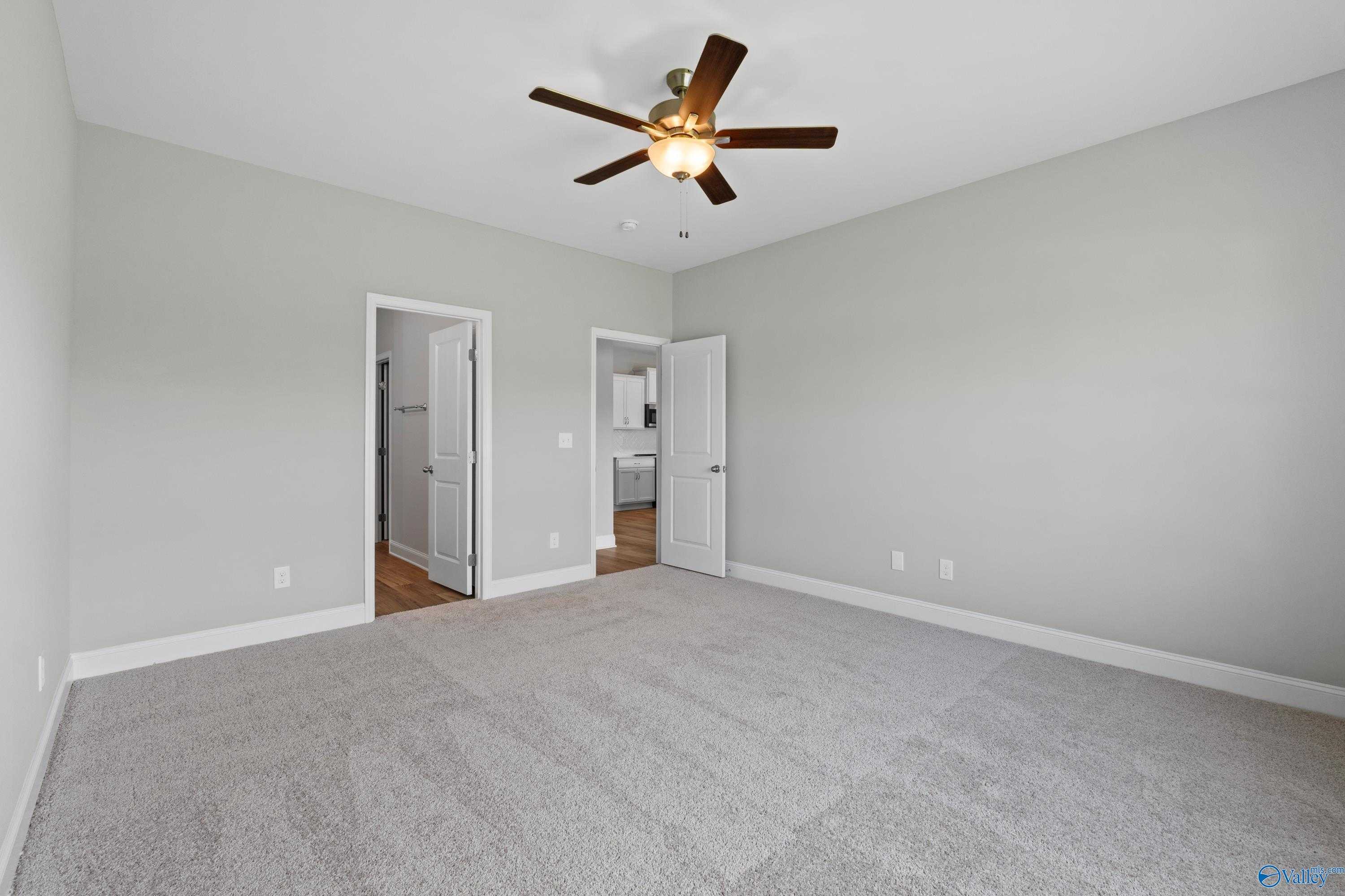Spacious secondary bedroom with gray walls, carpeted floor, ceiling fan, and attached bath in Davidson Homes The Daphne C, Athens, Alabama