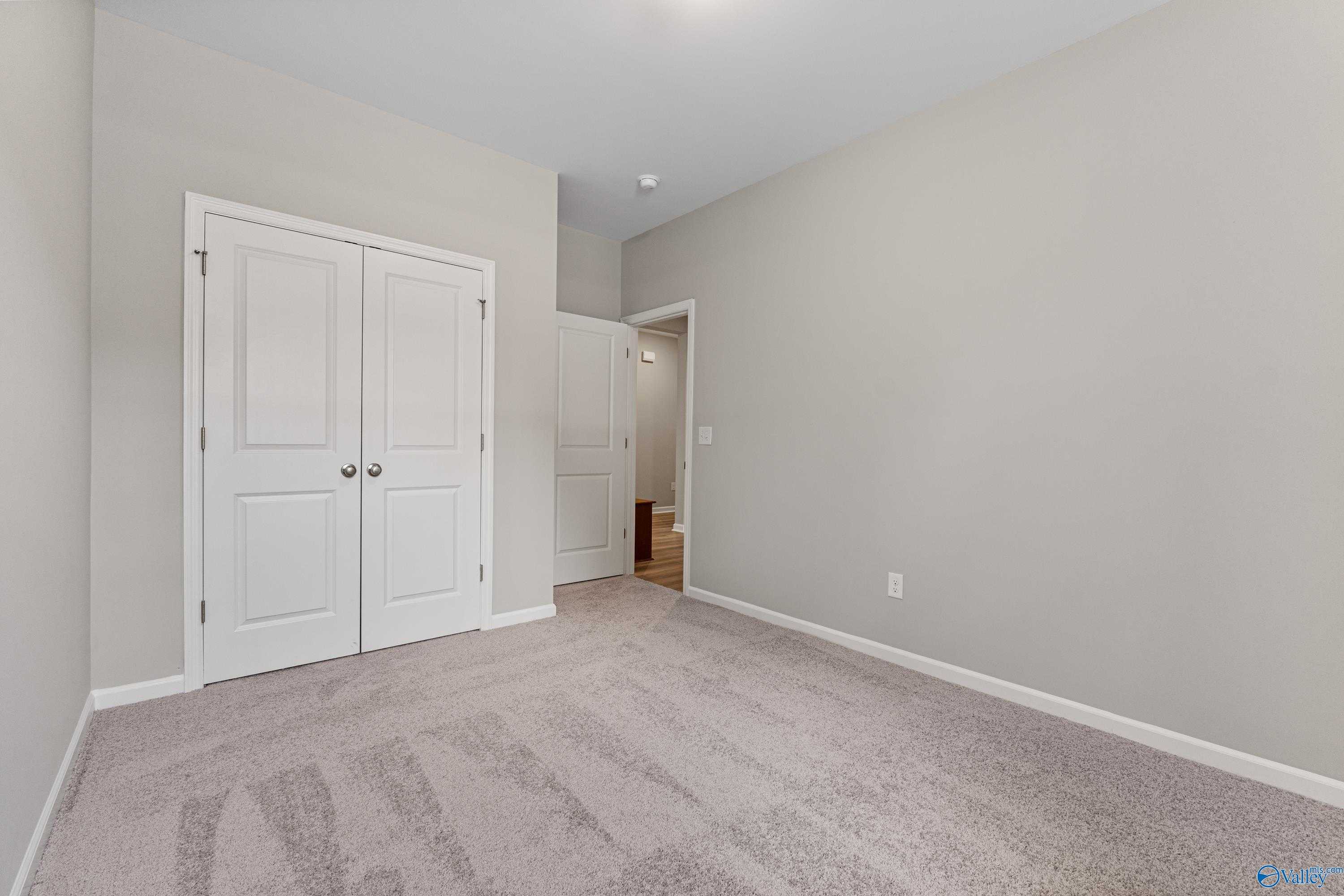Spacious secondary bedroom featuring gray walls, white double closet doors, and bathroom access in Davidson Homes The Aurora, Fayetteville, TN