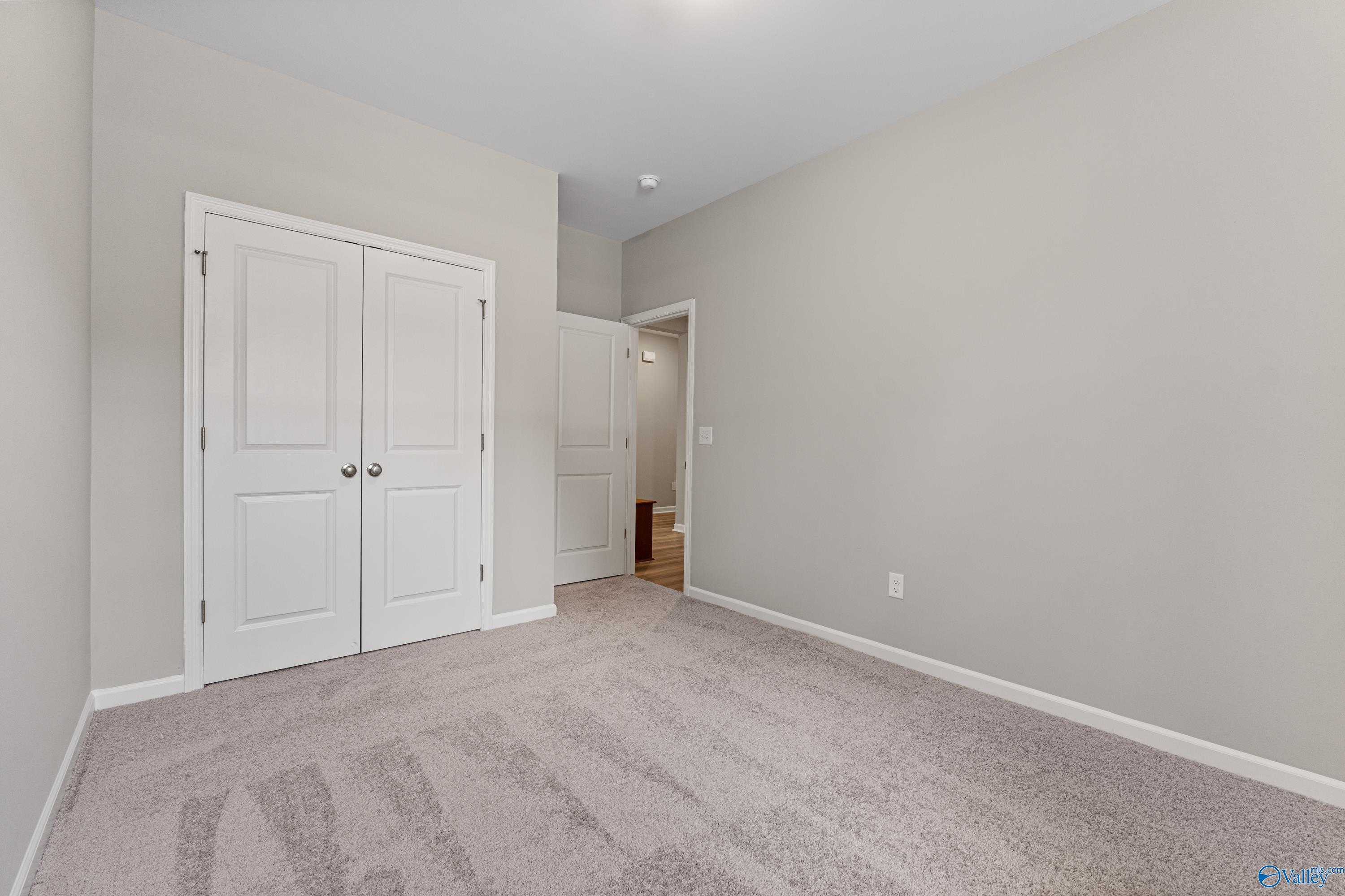 Spacious secondary bedroom with gray walls, double closet doors, and bath access in Davidson Homes The Aurora, Fayetteville, TN