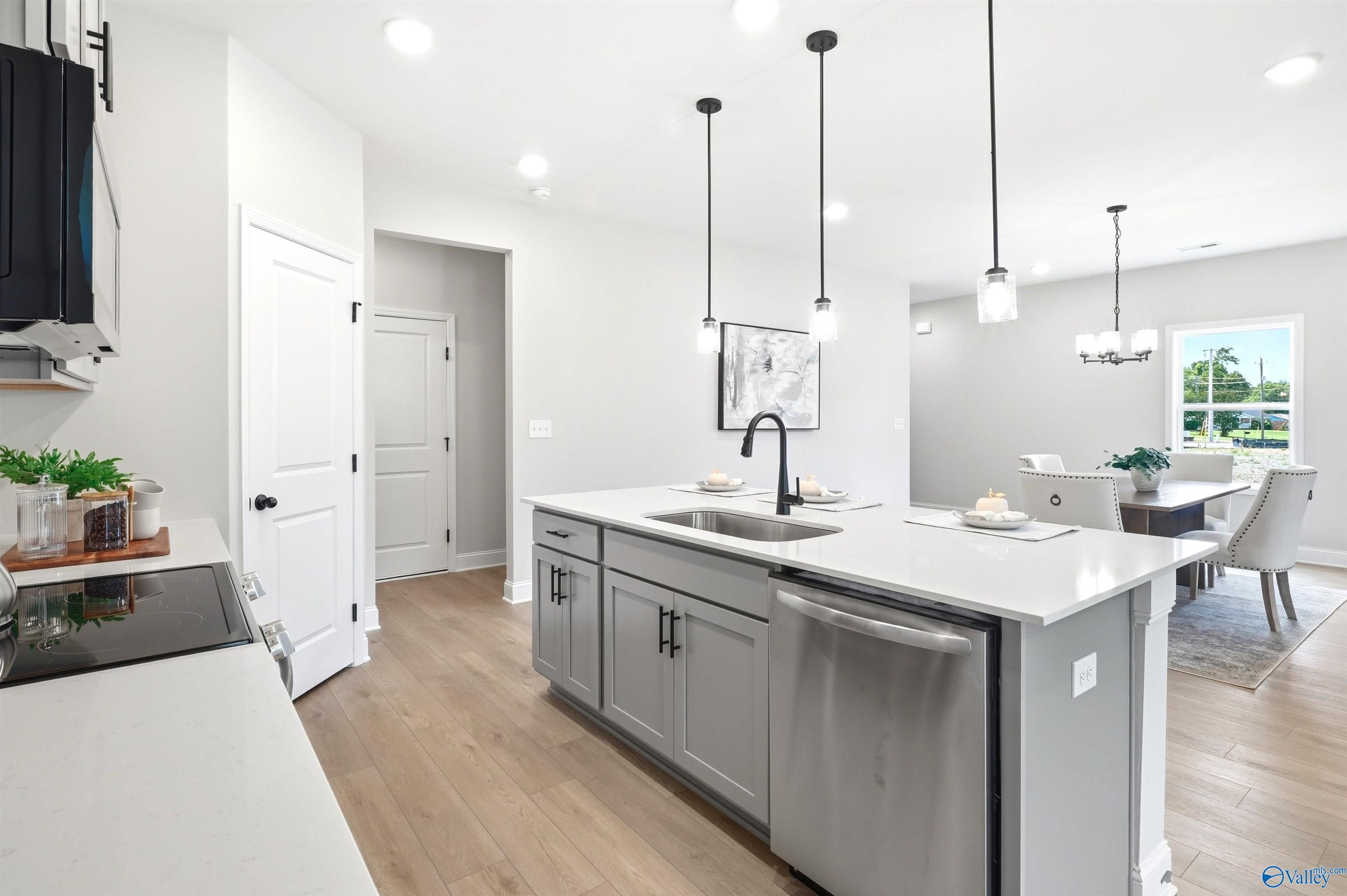 Gray kitchen island with sink, pendant lights, and dining area in Davidson Homes The Russell A plan at Spragins Cove, Huntsville