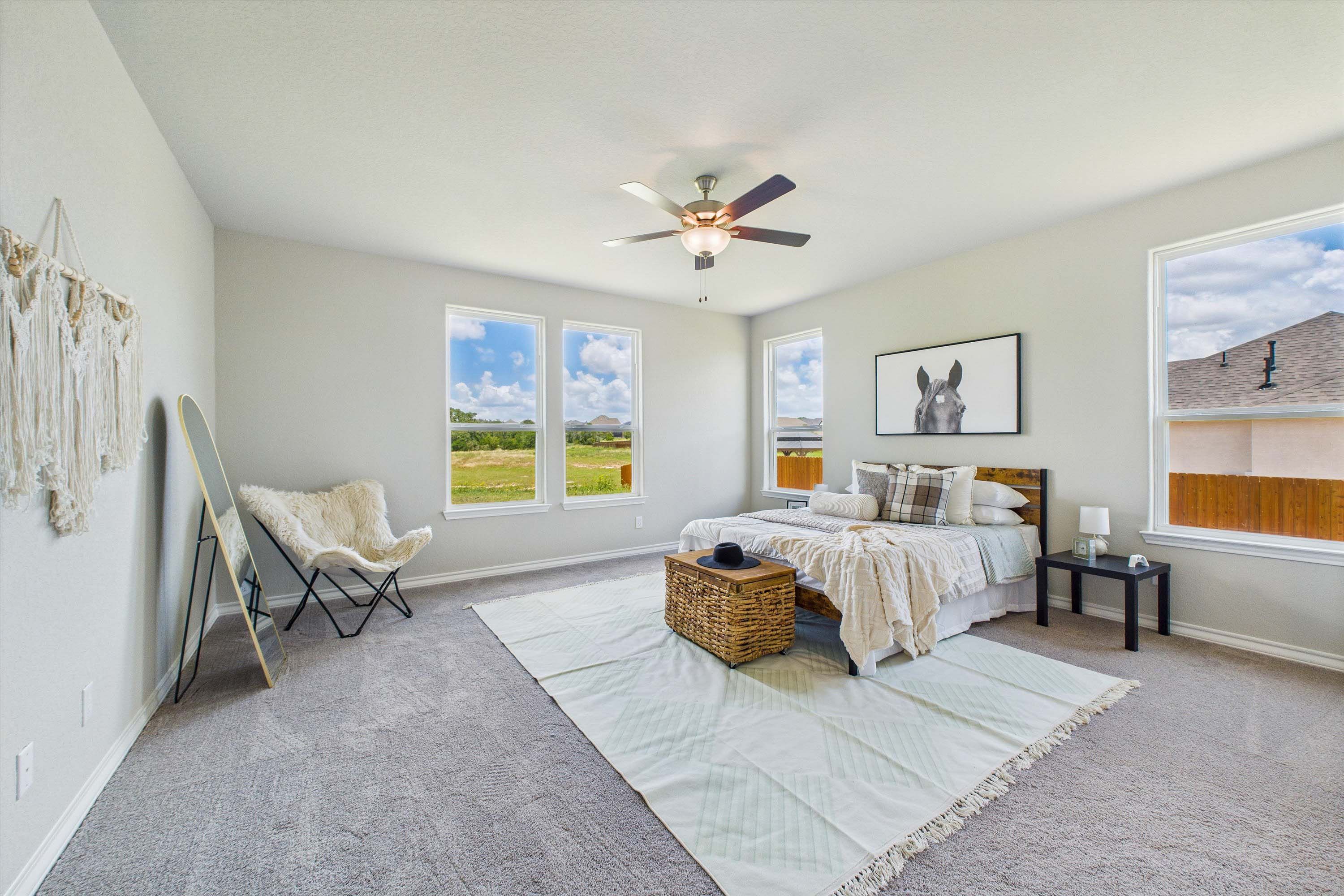 Spacious master suite in The Foster home design featuring large windows, neutral decor, and modern bedroom furnishings.
